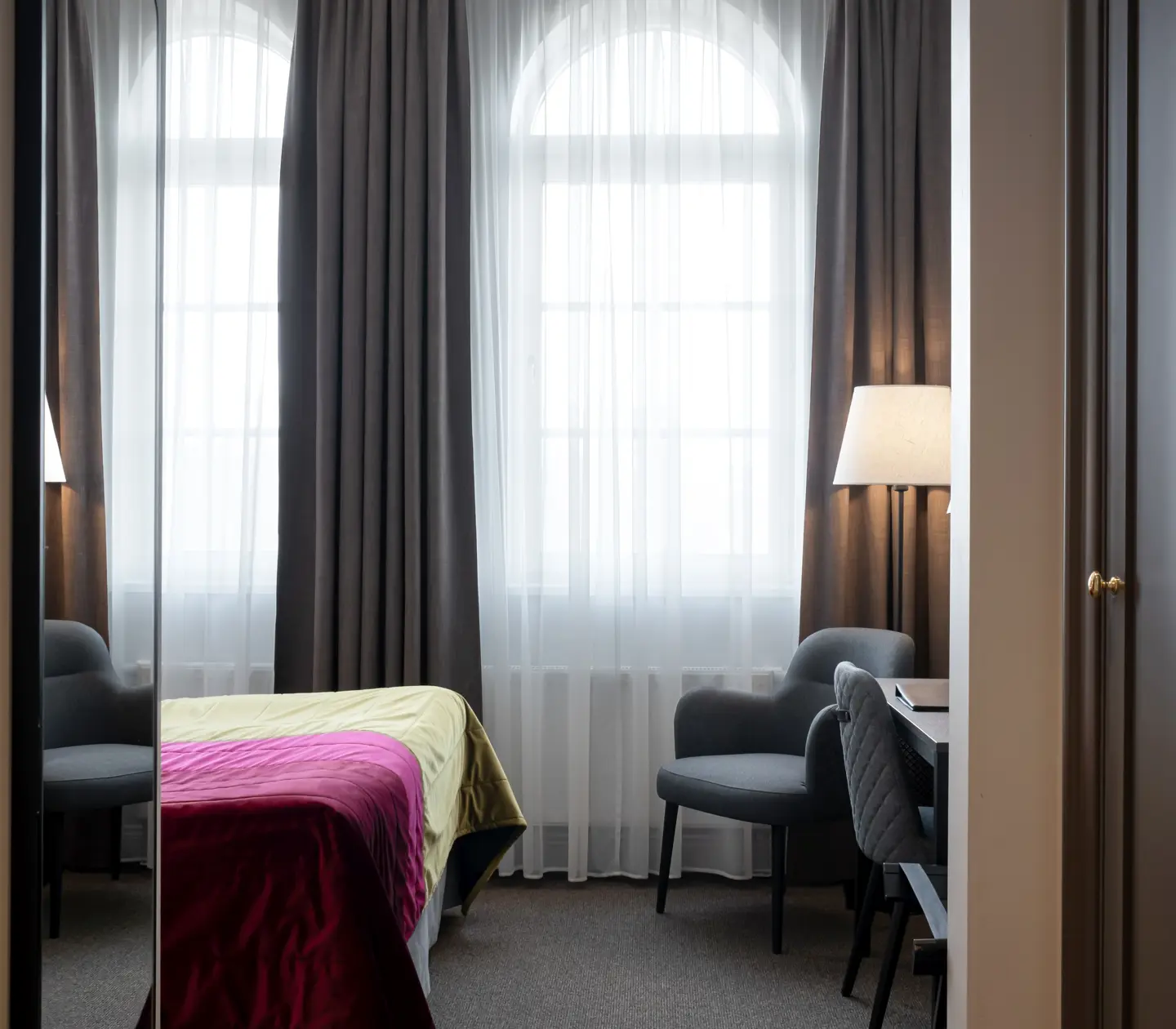 Hotel room with bed, desk and wardrobe