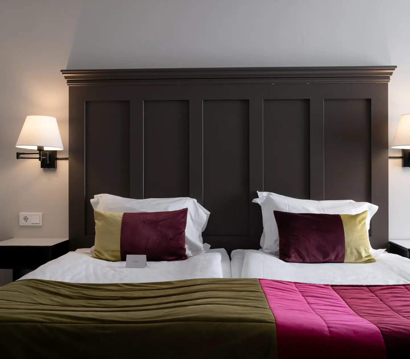 Hotel room with bed, large wooden headboard and bedside lamps