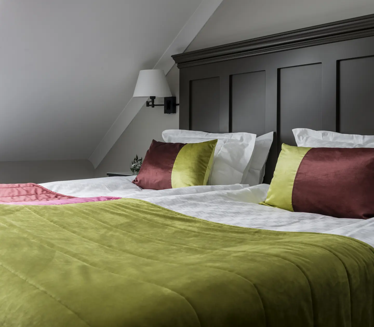 Hotel room with bed, large wooden headboard and slanted ceiling