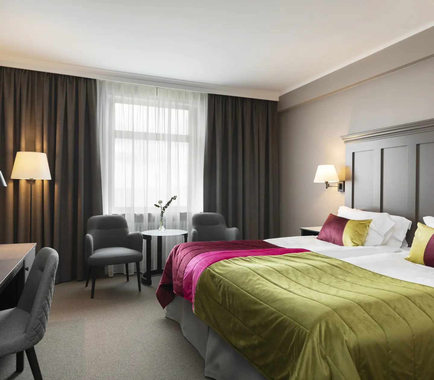 Hotel room with bed, desk and armchairs