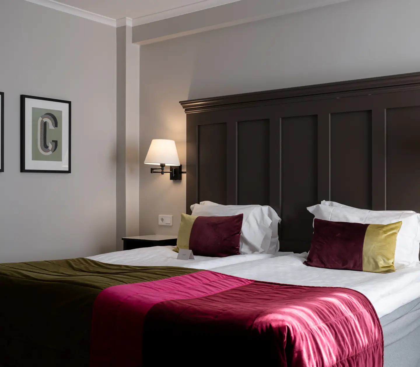 Hotel room with bed, large wooden headboard and paintings