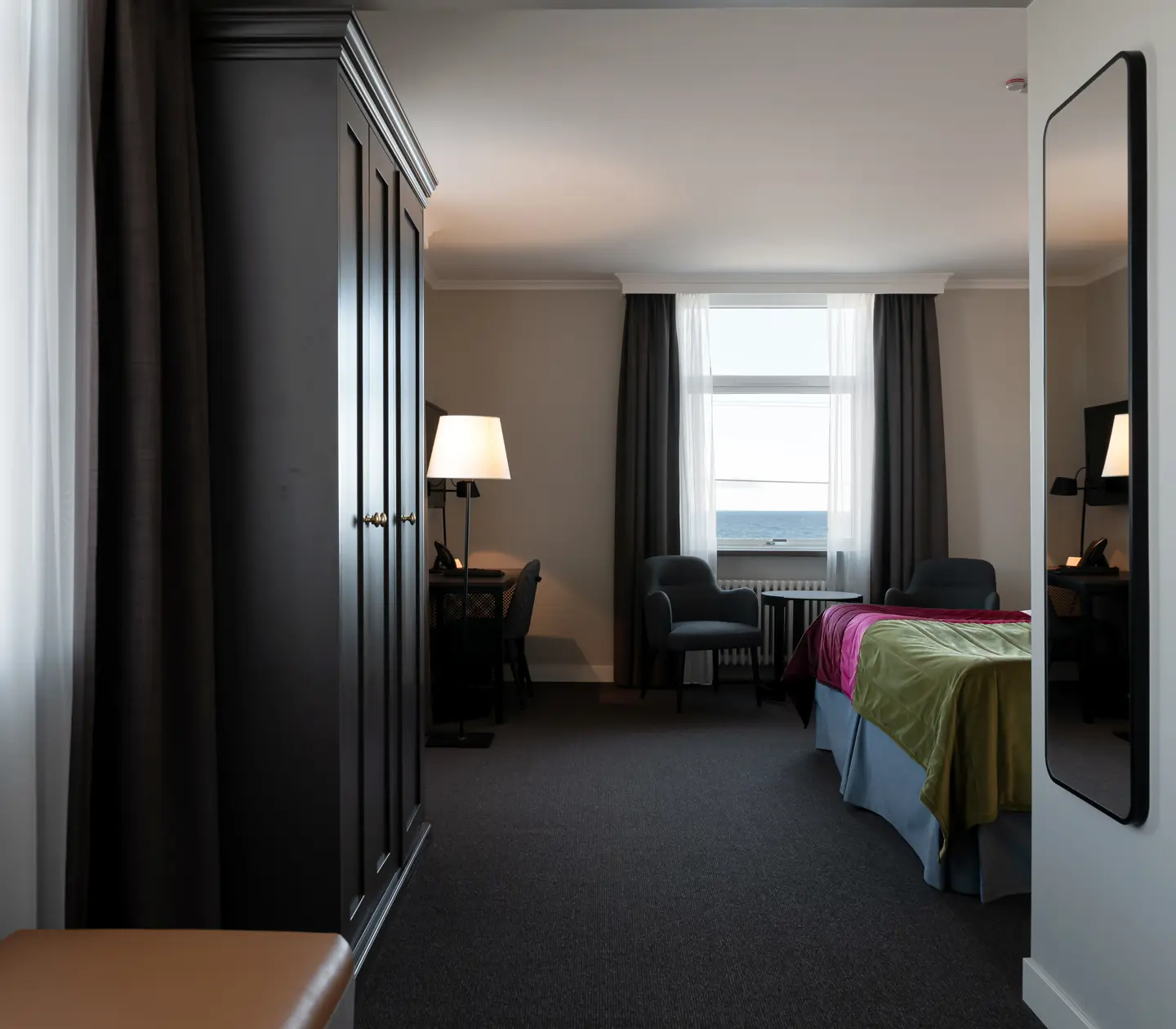 Hotel room with wardrobe, desk and sea view
