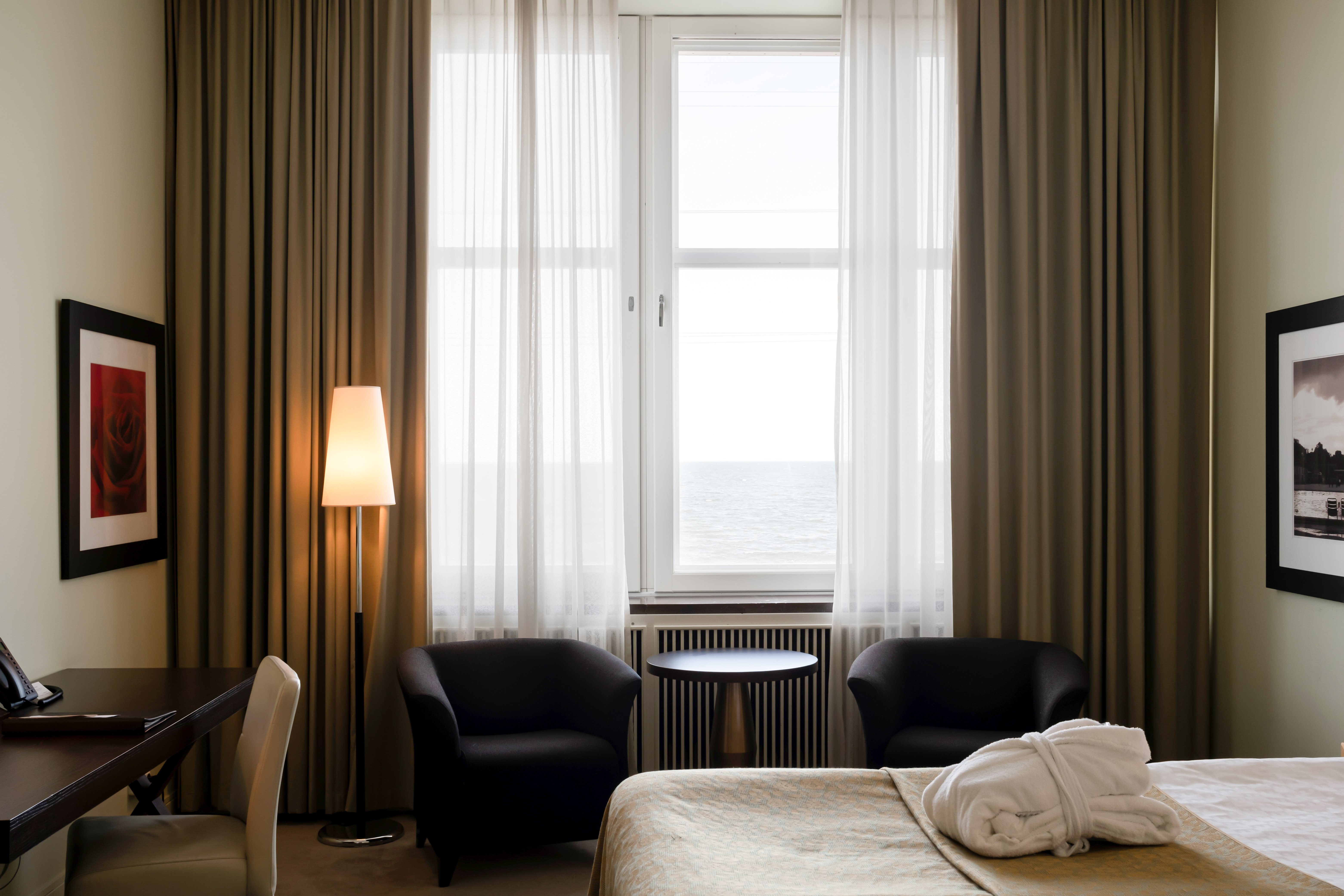 Hotellrum med säng, fåtöljer och havsutsikt