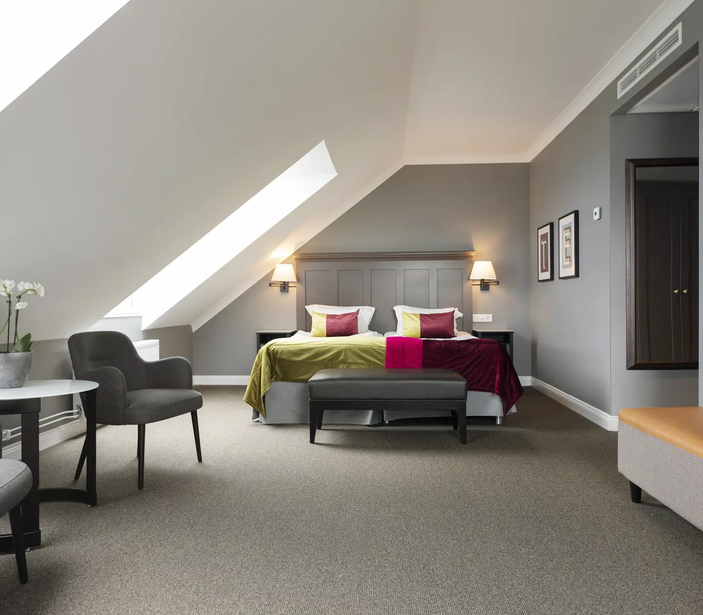 Hotel room with bed, armchairs and sloping ceiling