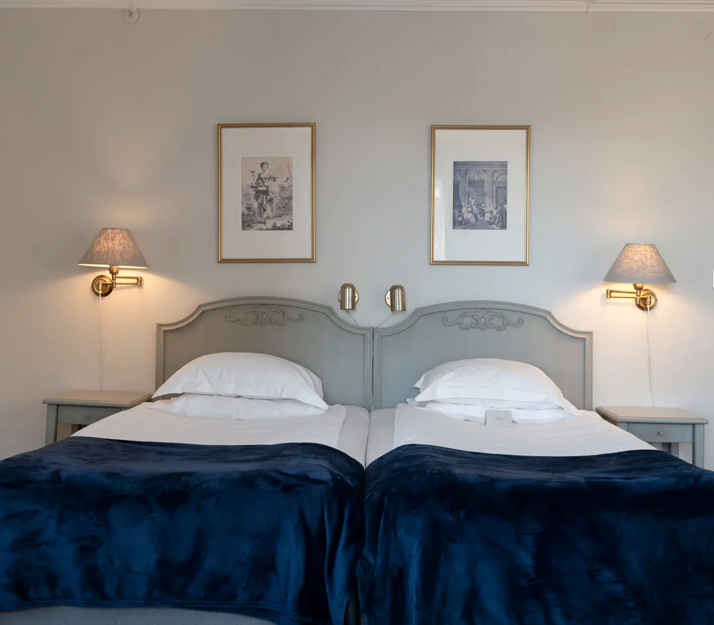 Hotel room with bed, paintings and bedside lamps