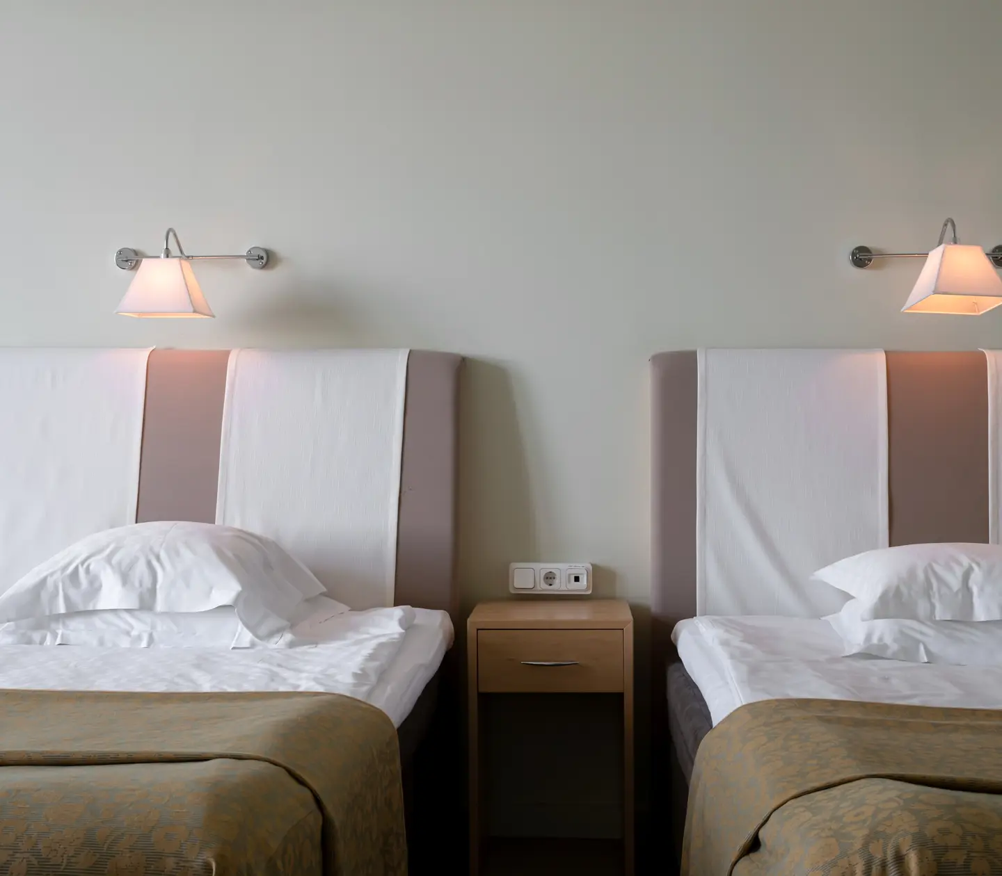 Hotel rooms with beds, bedside tables and bedside lamps
