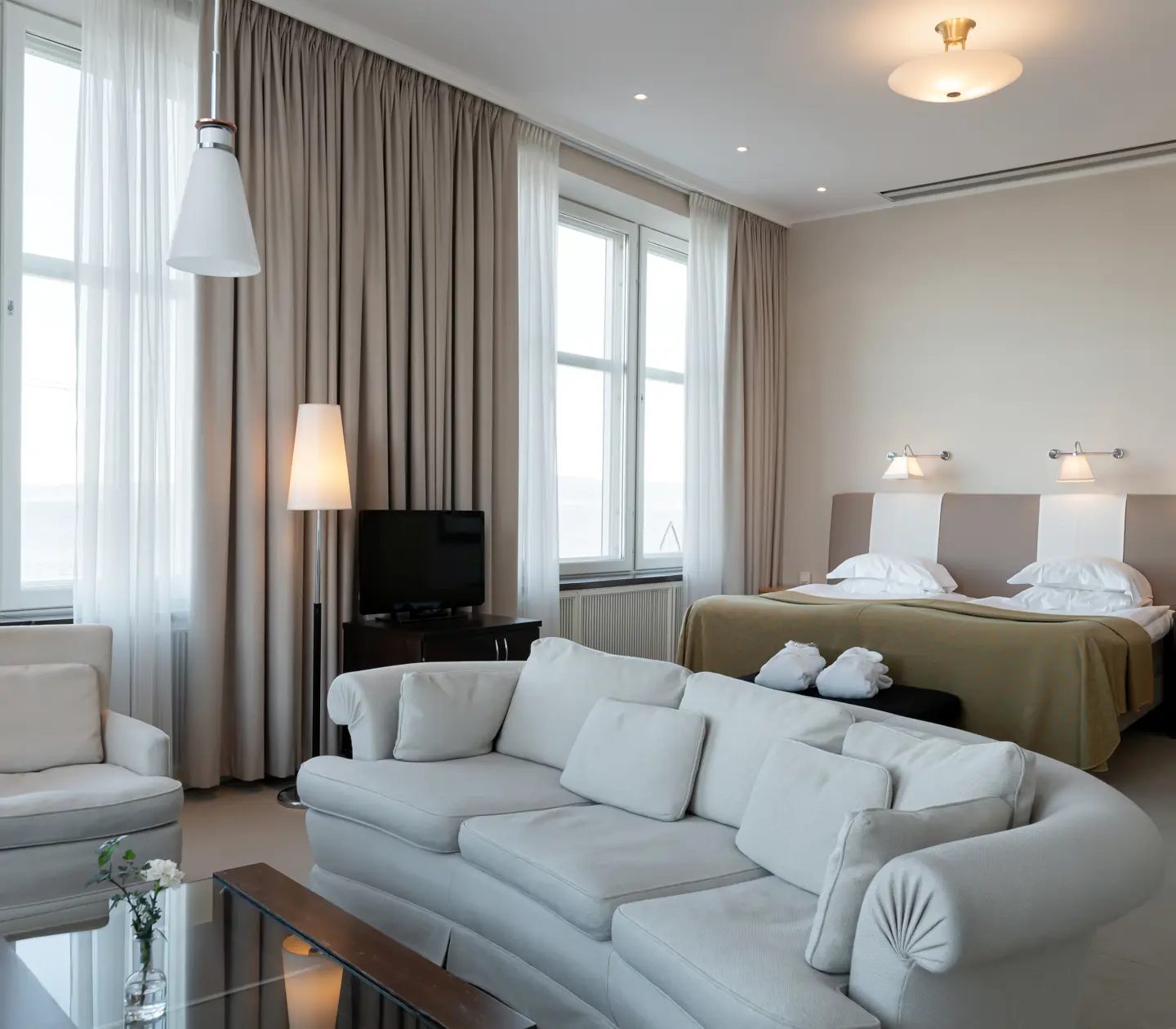 Suite with bed, sitting area and large windows