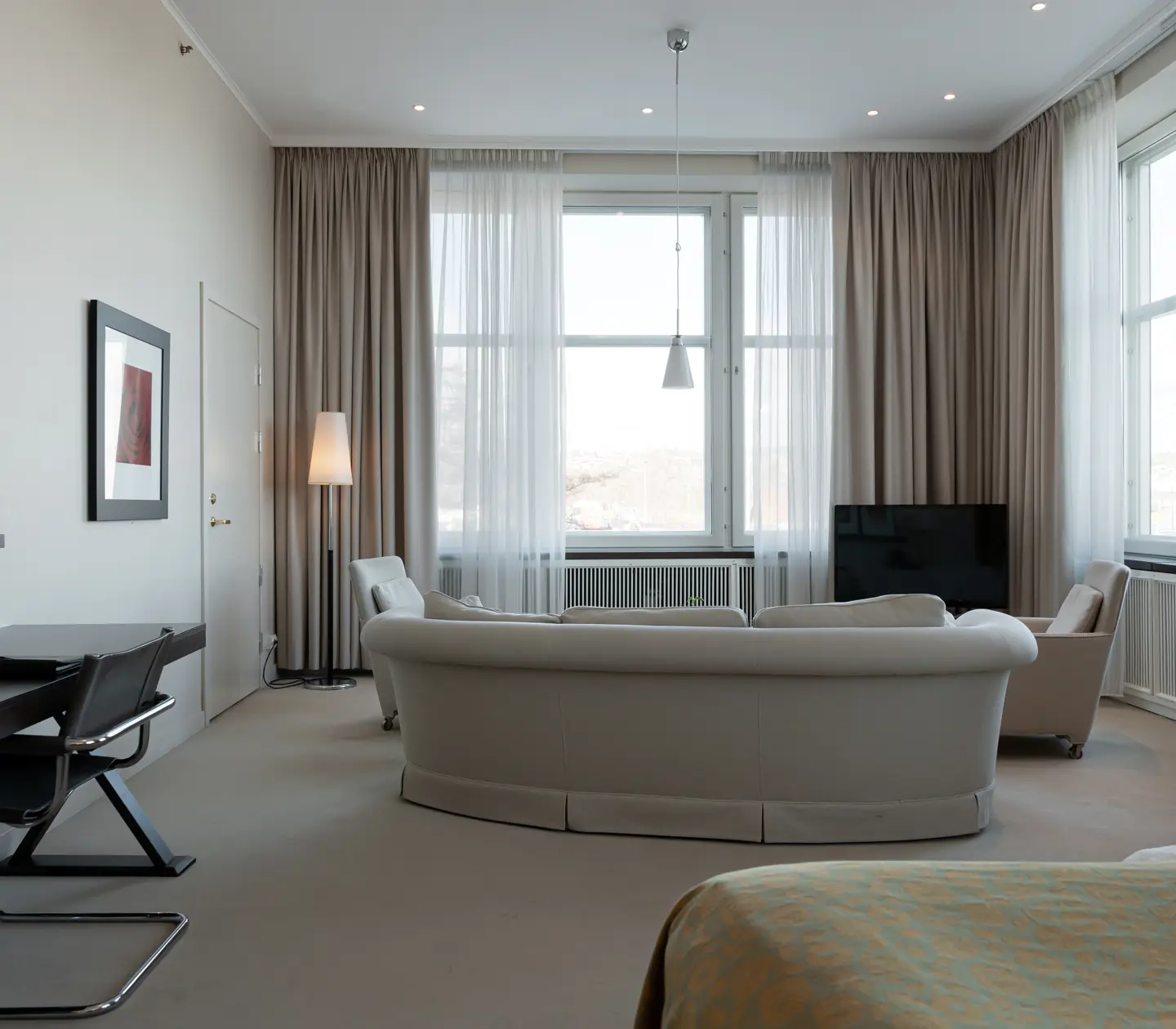 Suite with bed, sitting area and large windows
