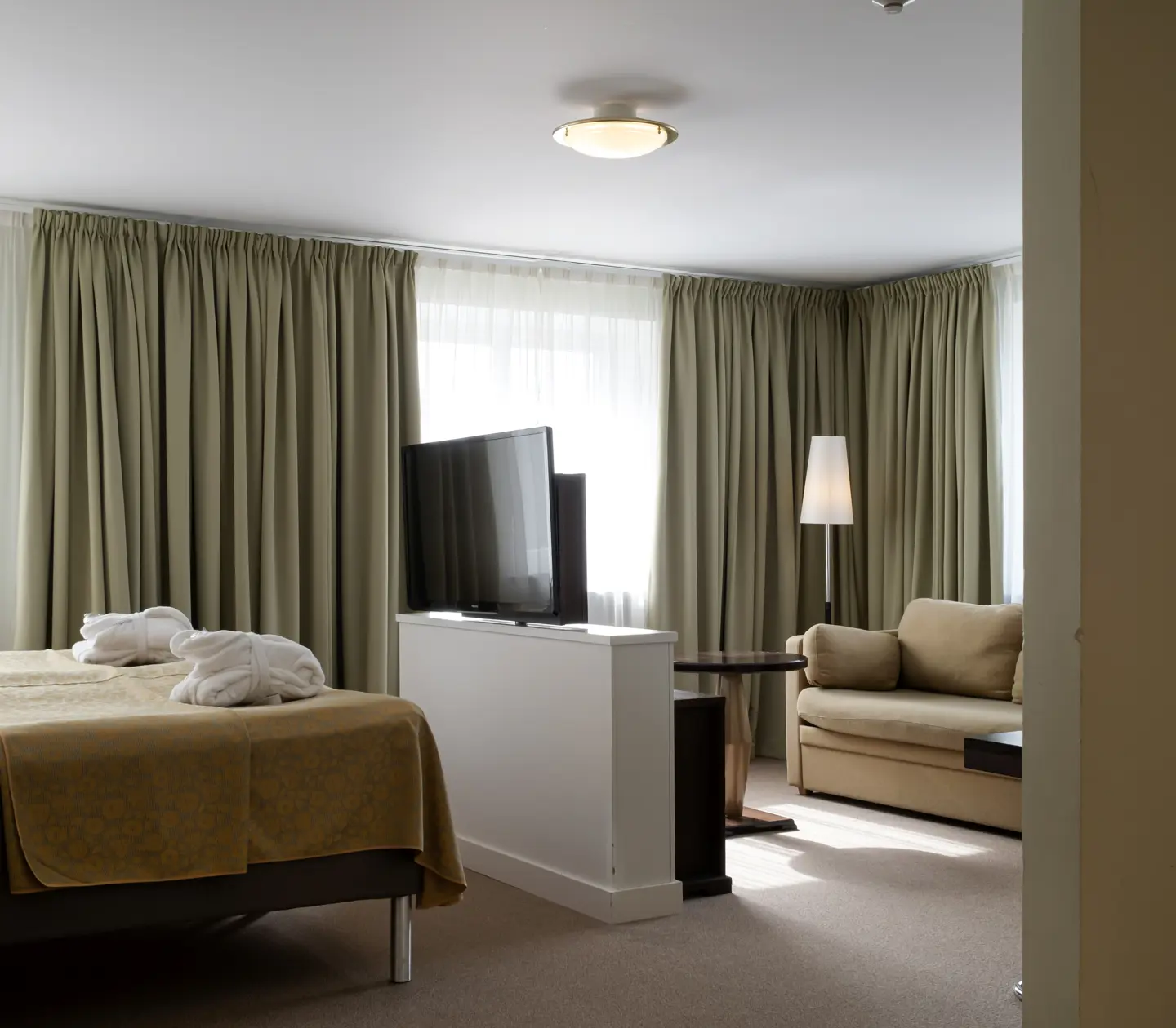 Suite with bed, TV and large windows