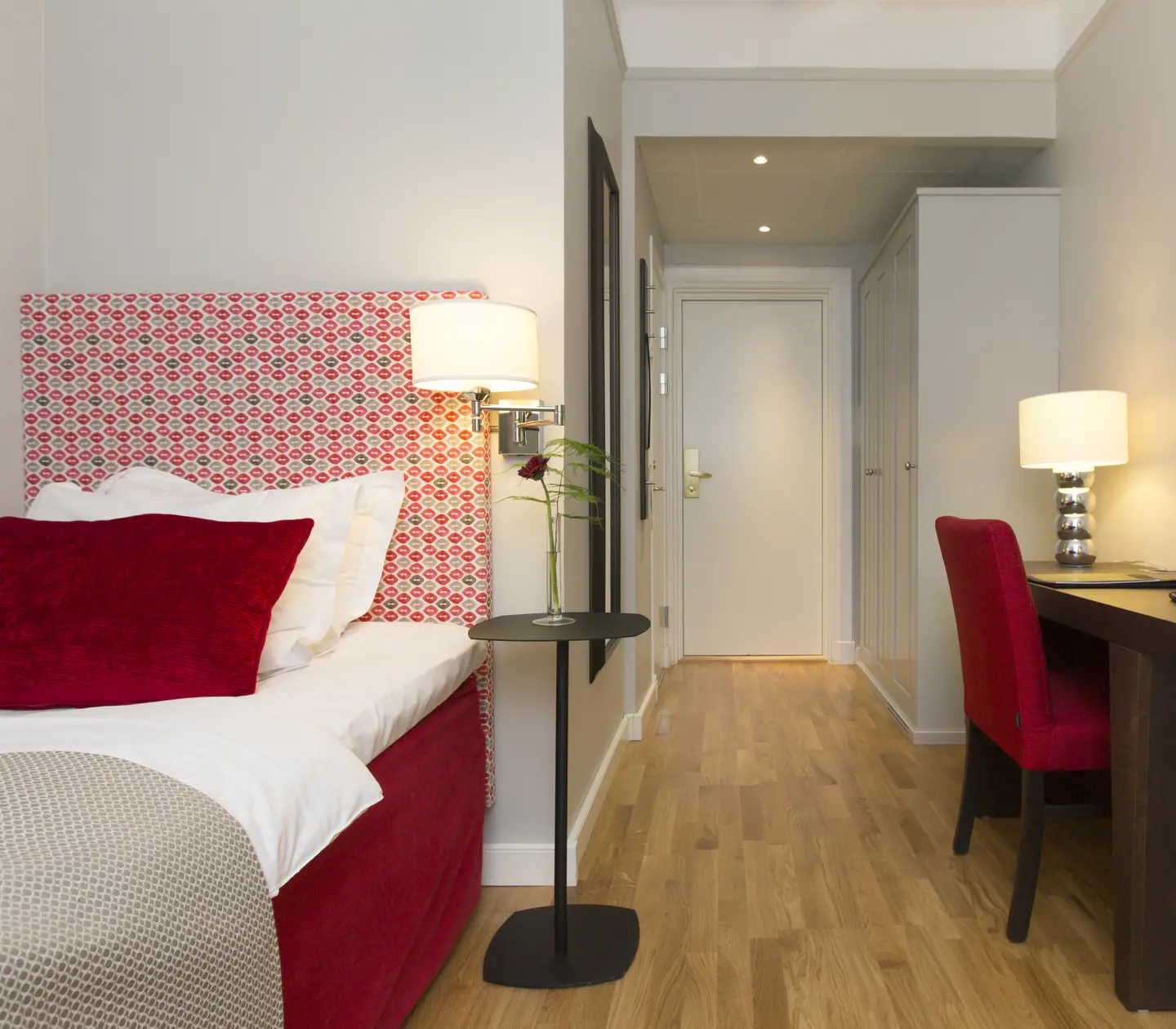 Hotel room with single bed, lamps and desk