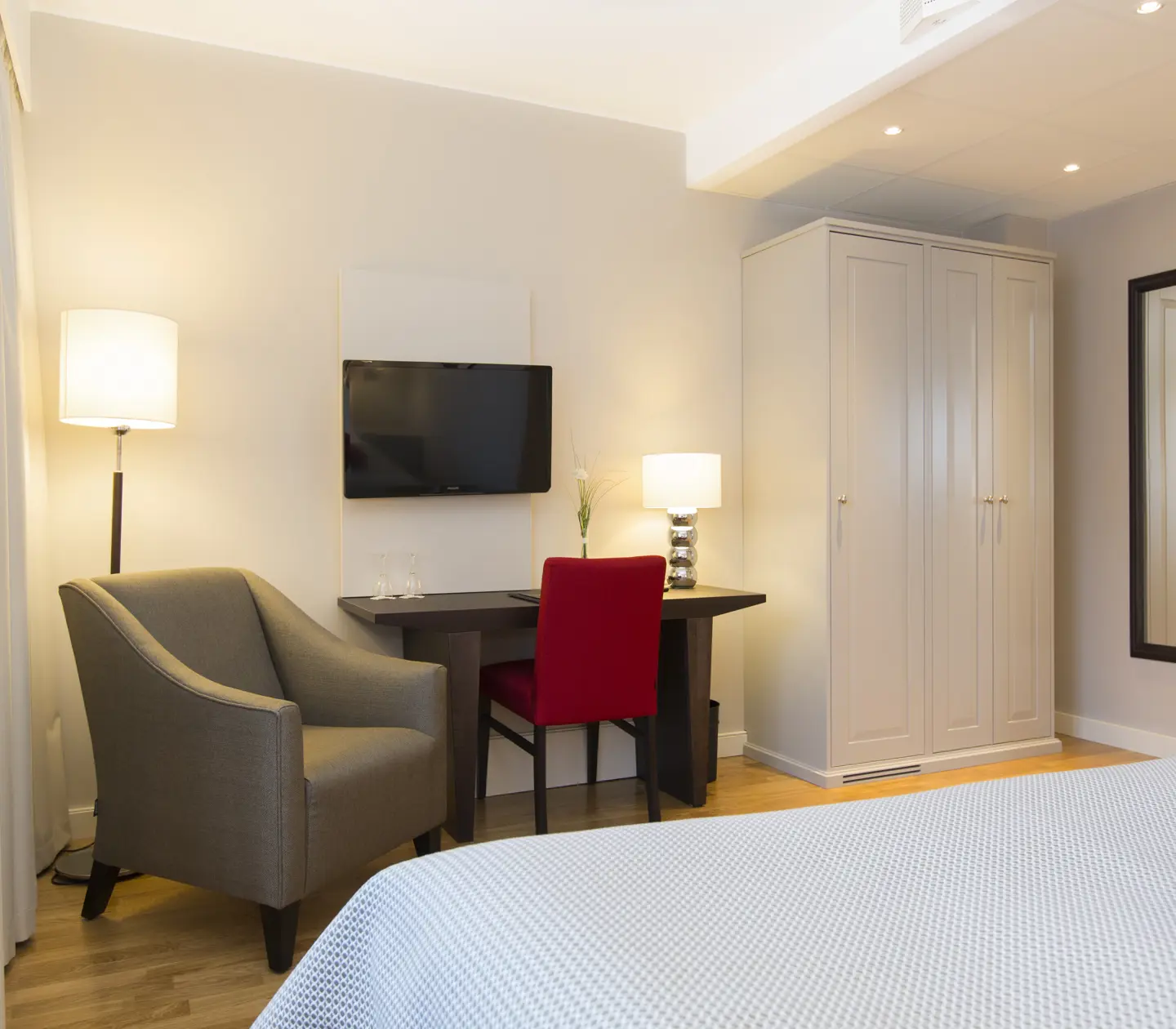 Hotel room with wardrobe, desk and armchair