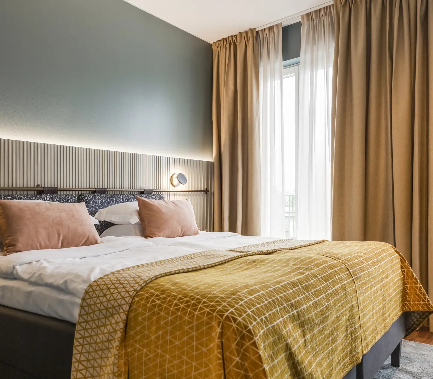 Comfortable hotel room with double bed, warm textiles and large windows