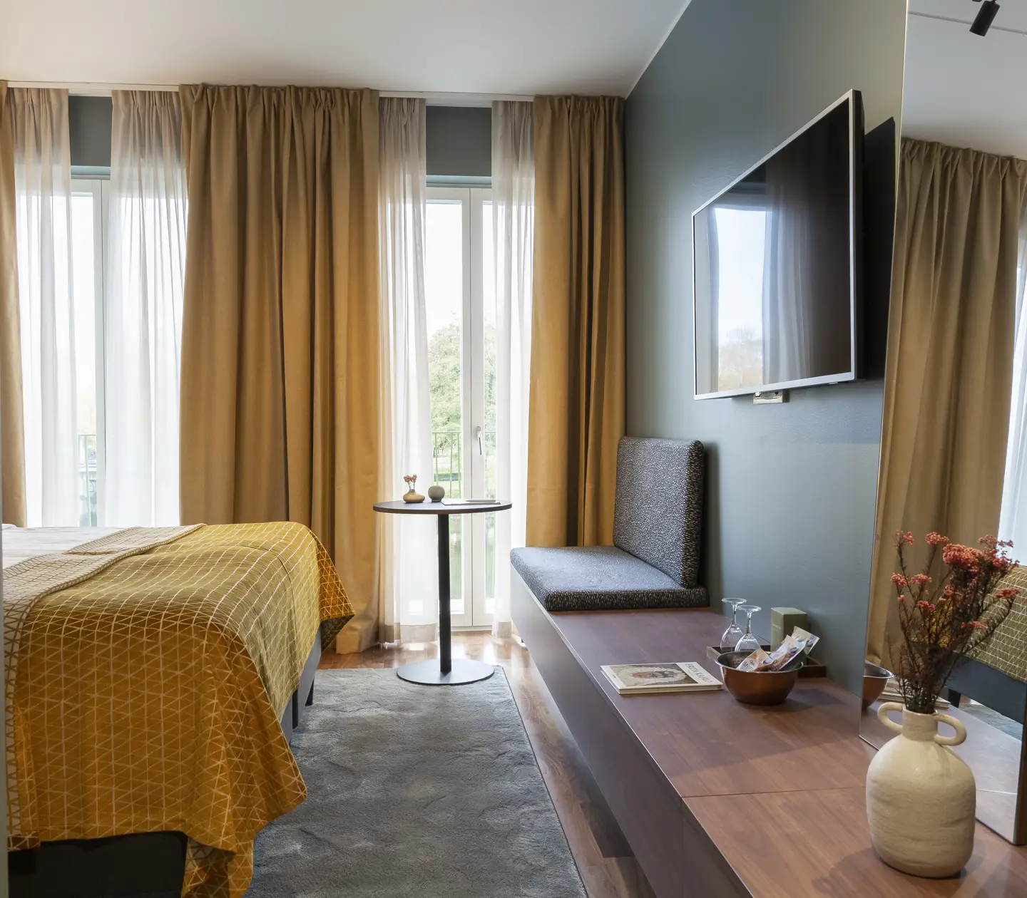 Comfortable hotel room with TV, warm textiles and large windows