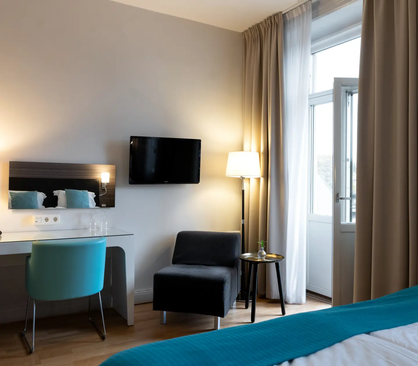 Hotel room with double bed, desk and balcony door