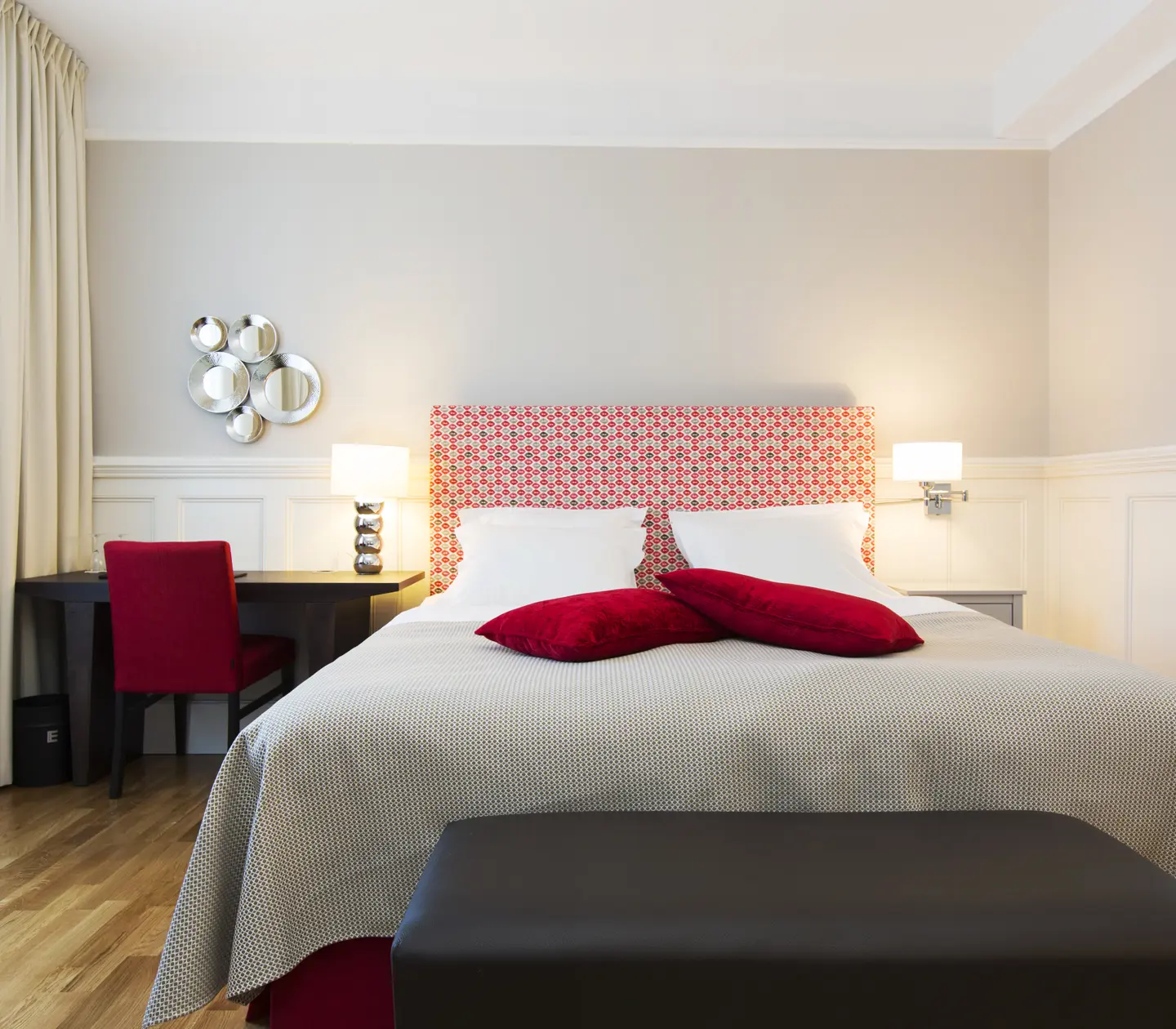 Bright hotel room with bed, red headboard and desk