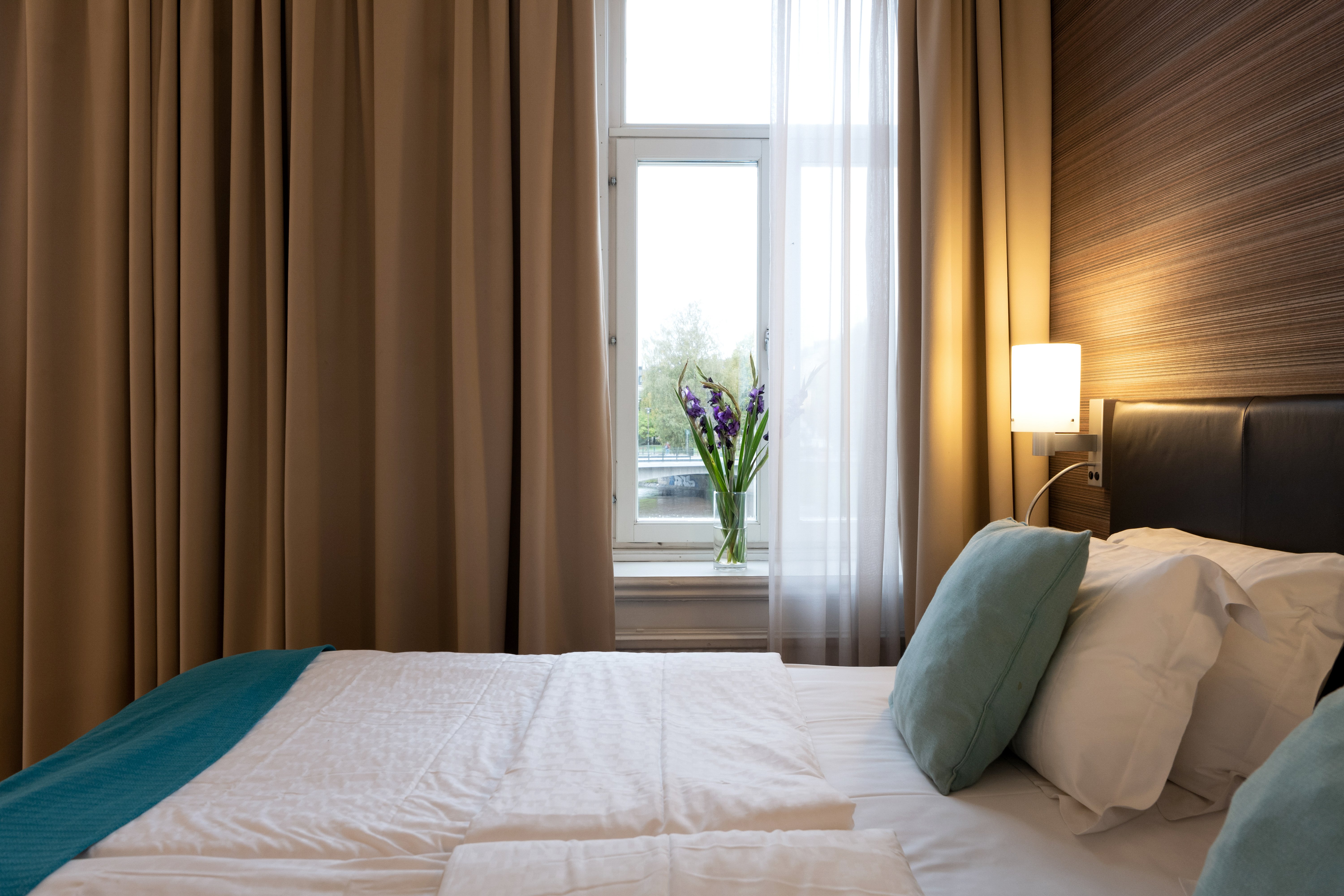 Ombonat hotellrum med dubbelsäng, varma textiler och stora fönster