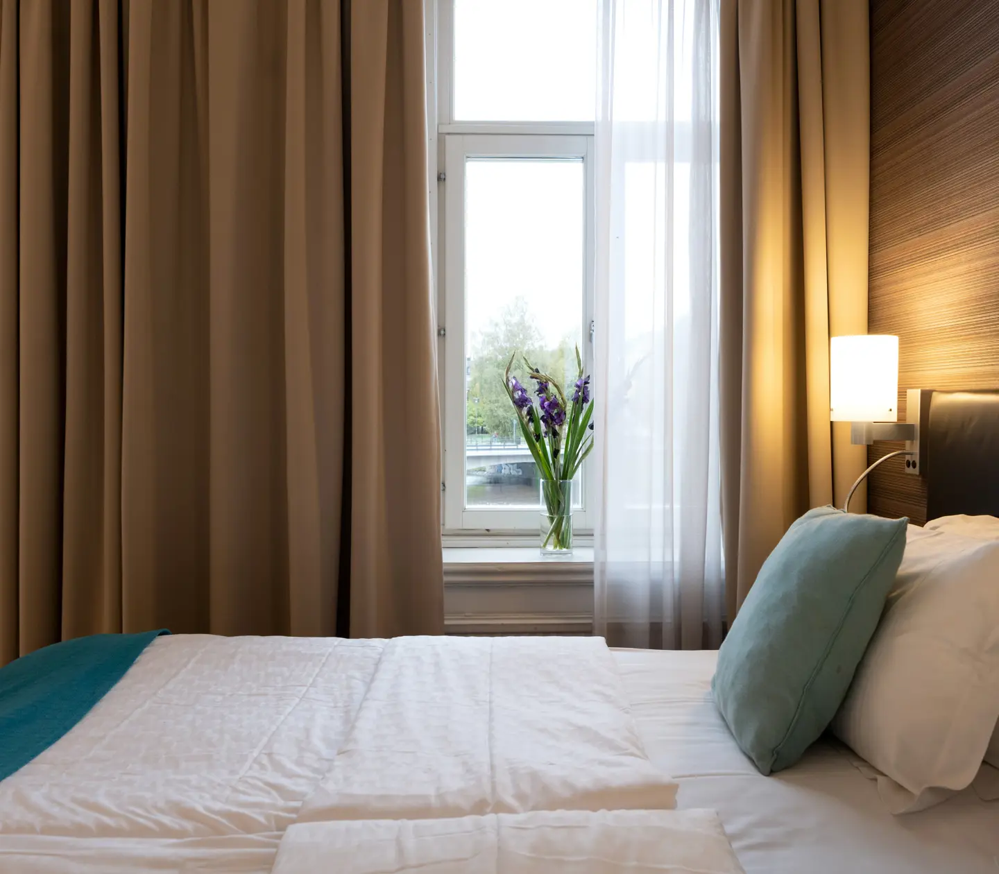 Comfortable hotel room with double bed, warm textiles and large windows