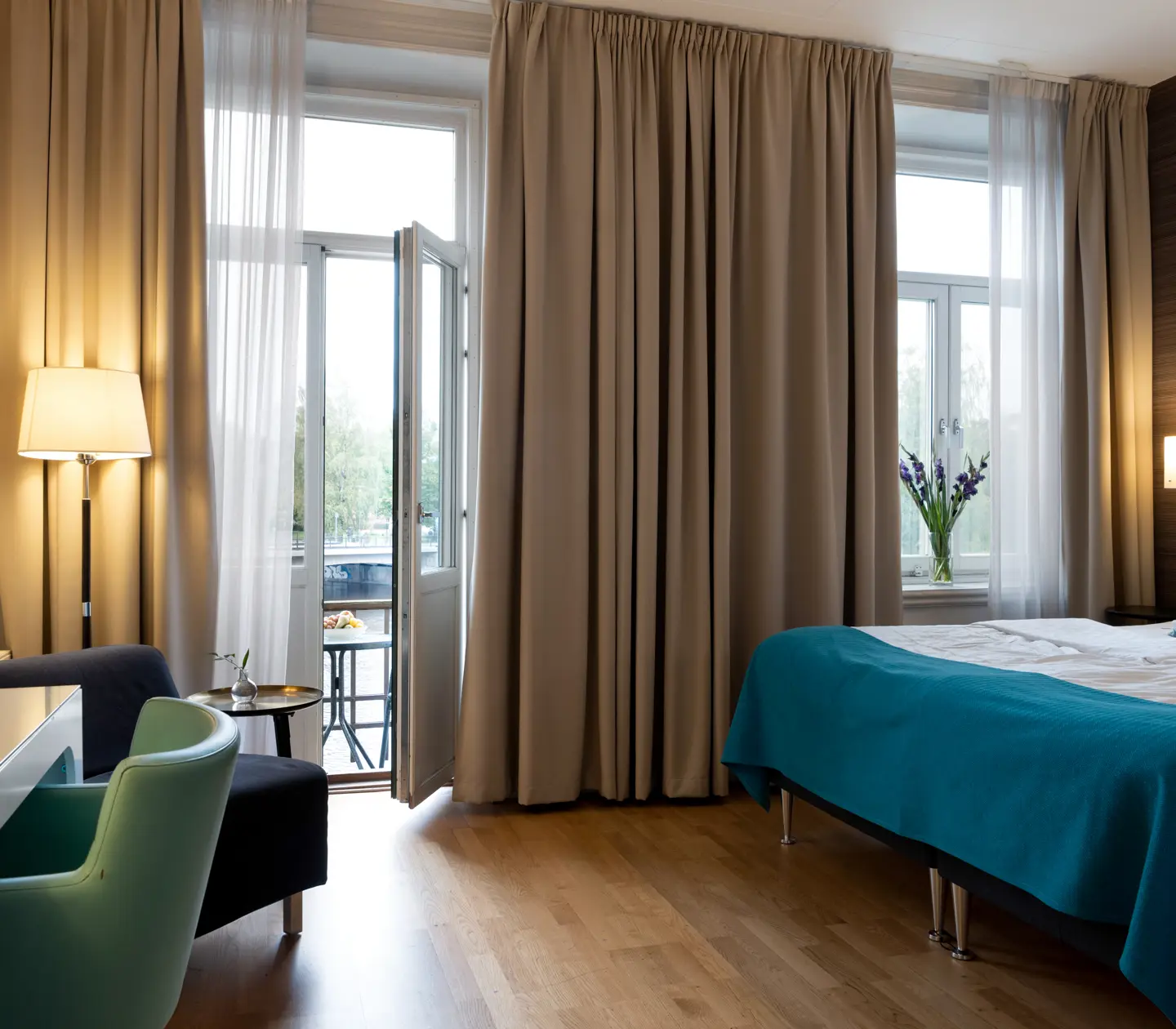 Comfortable hotel room with double bed, desk and balcony door