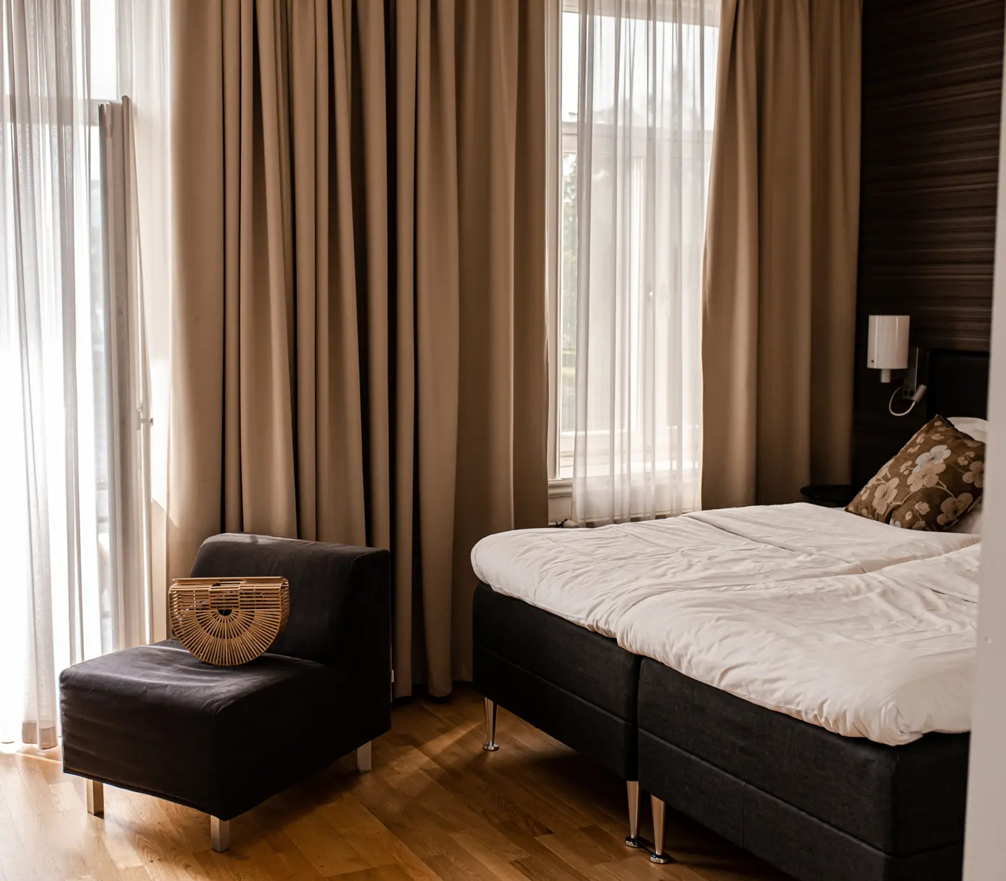 Comfortable hotel room with double bed, warm textiles and large windows