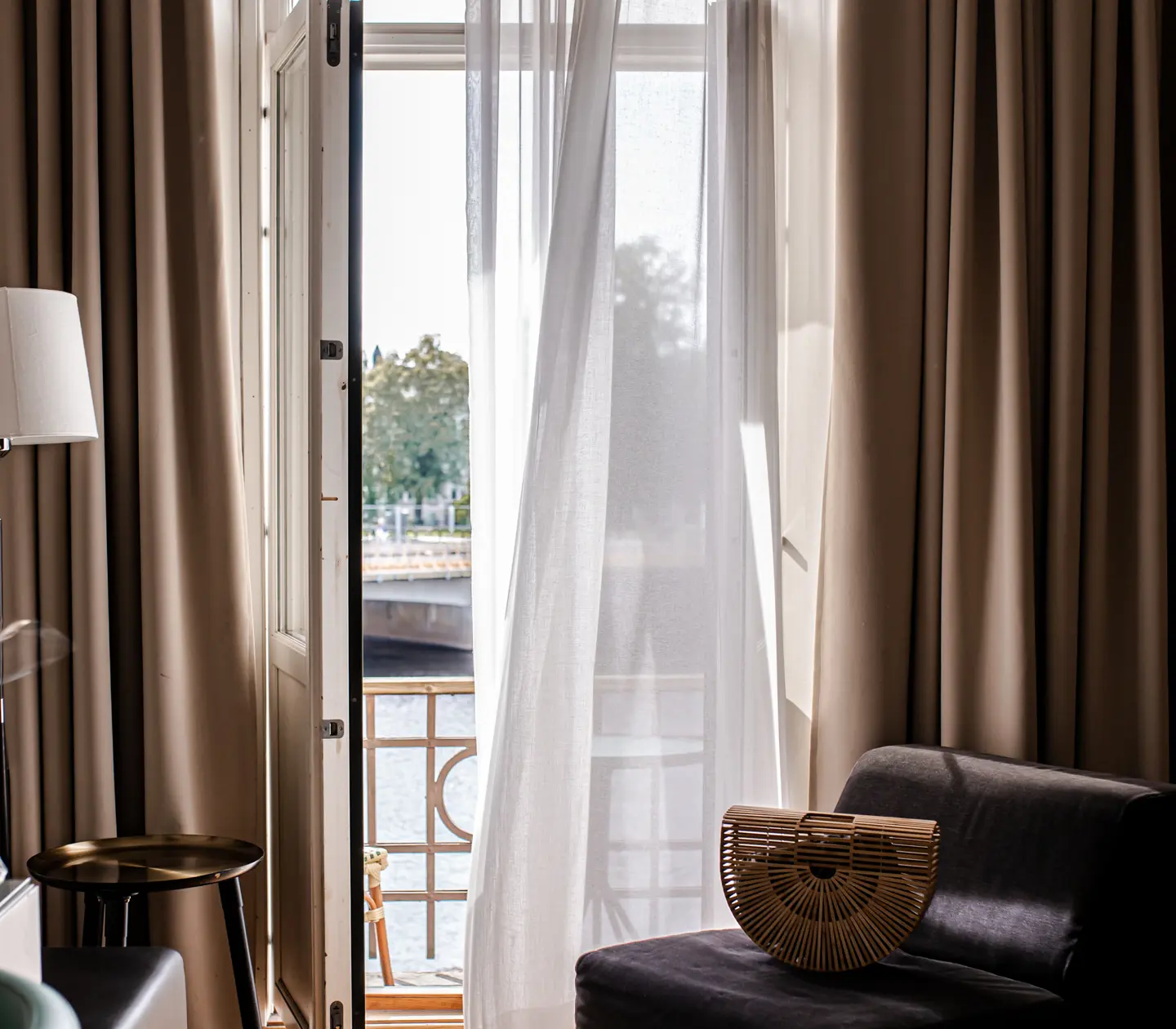 Cozy hotel room with open balcony door, warm textiles and bag