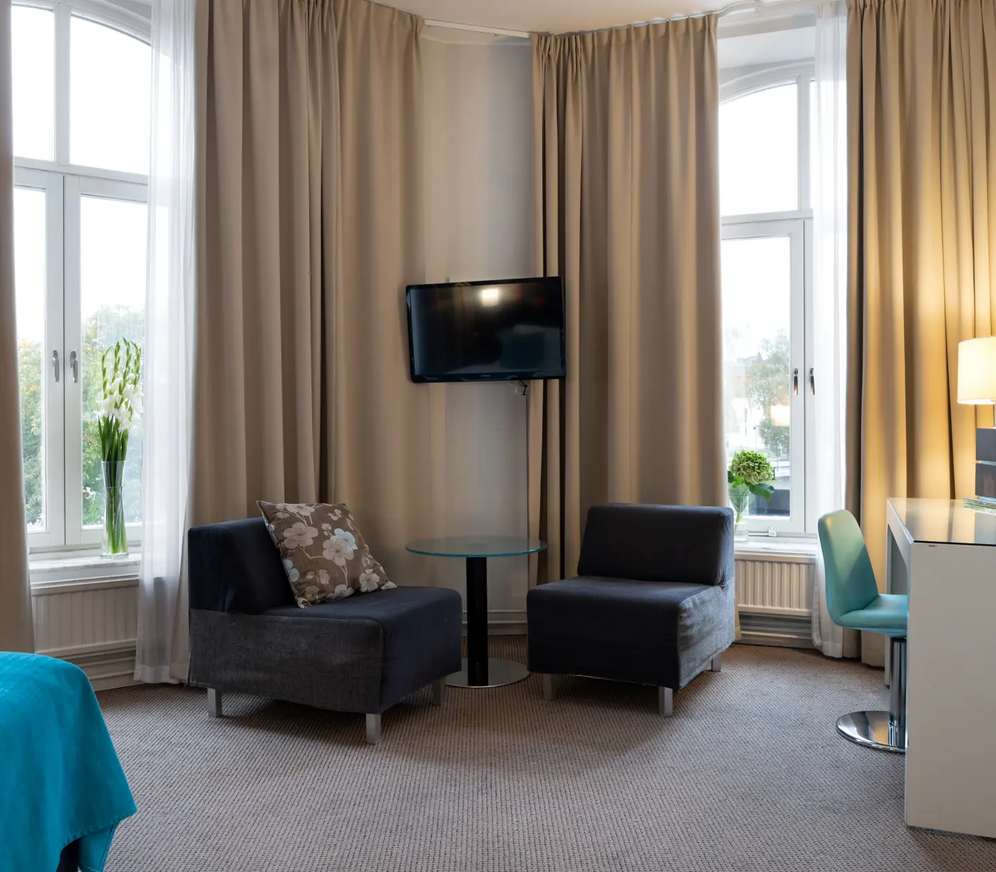 Bright hotel room with armchairs, desk and large windows