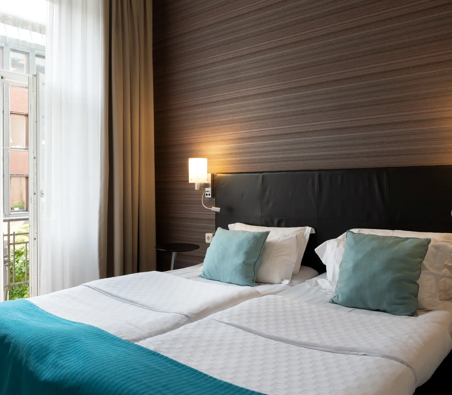 Hotel room with double bed, bedside lamps and open balcony door