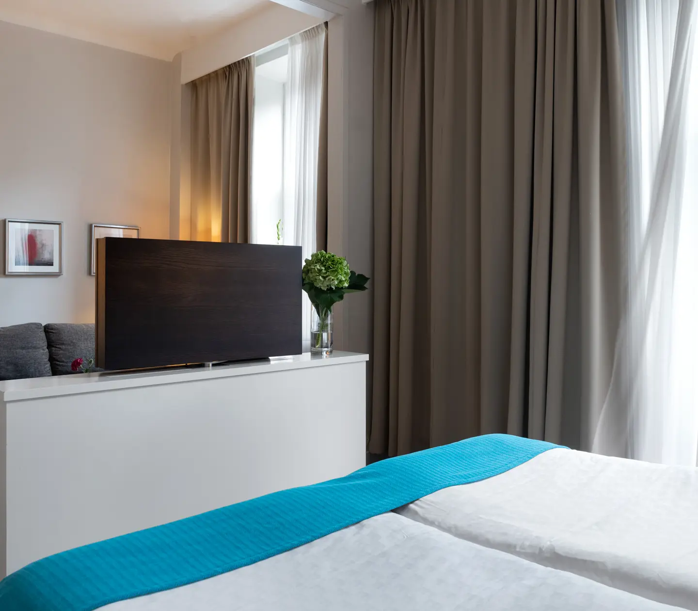 Bright hotel room with sofa, TV and large windows