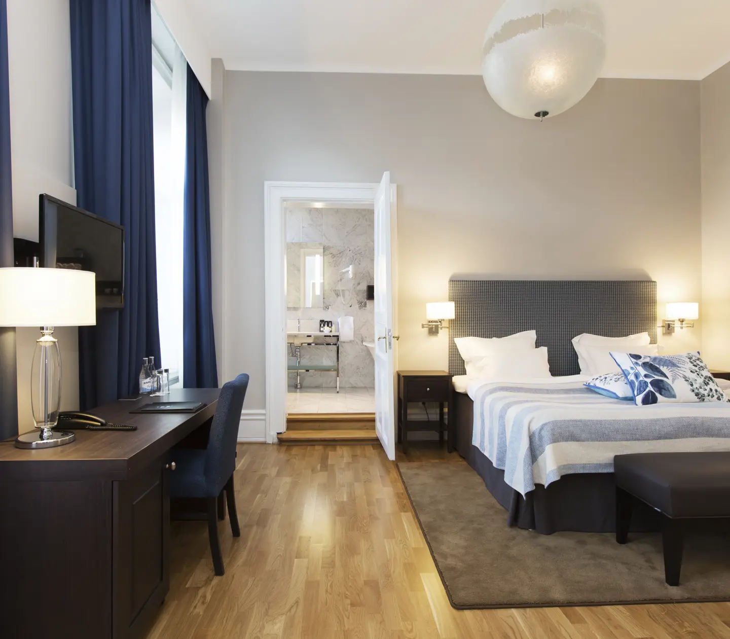 Bright suite with bed, desk and door to bathroom
