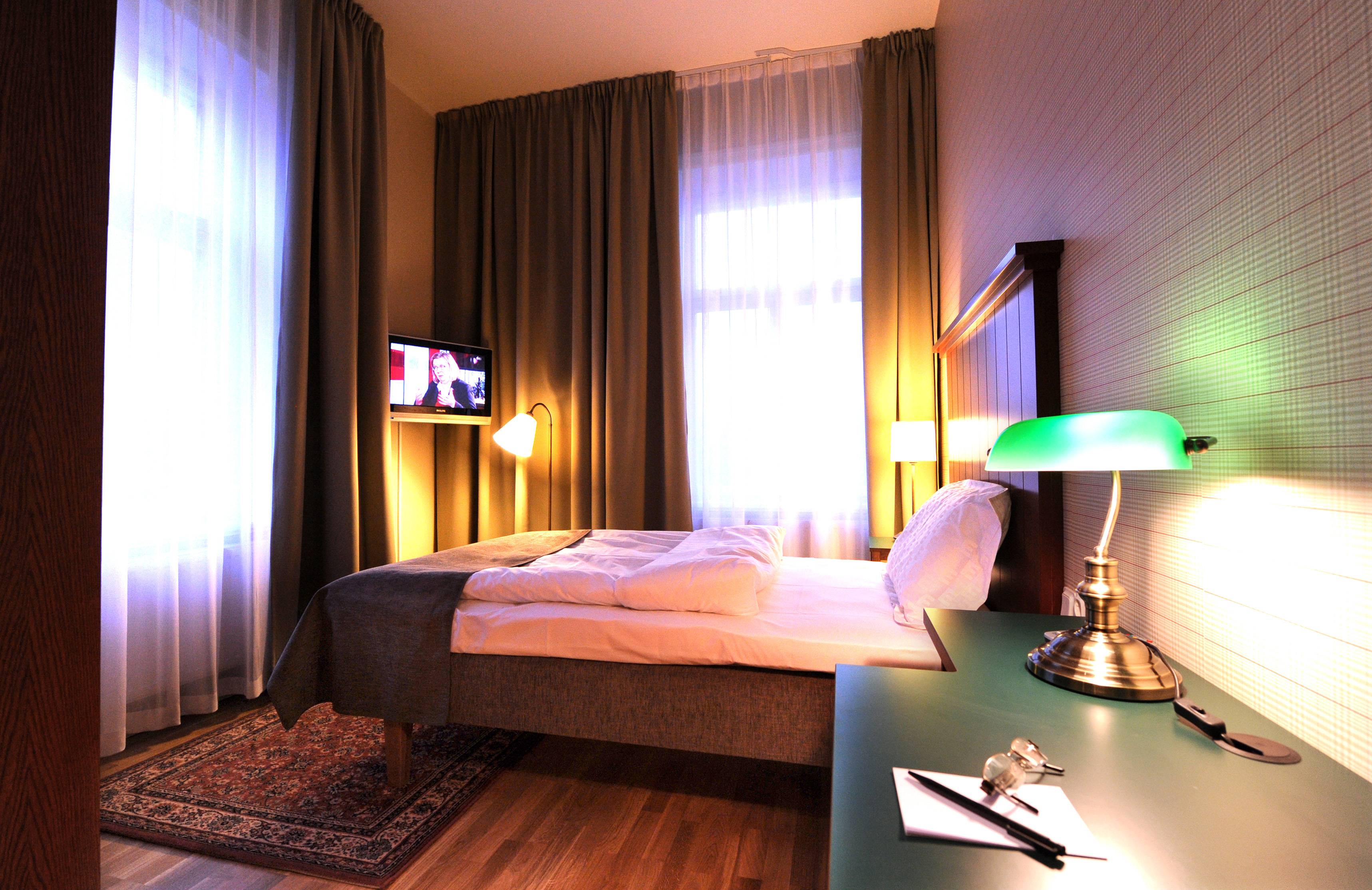 Hotellrum med säng, stor sänggavel och tv