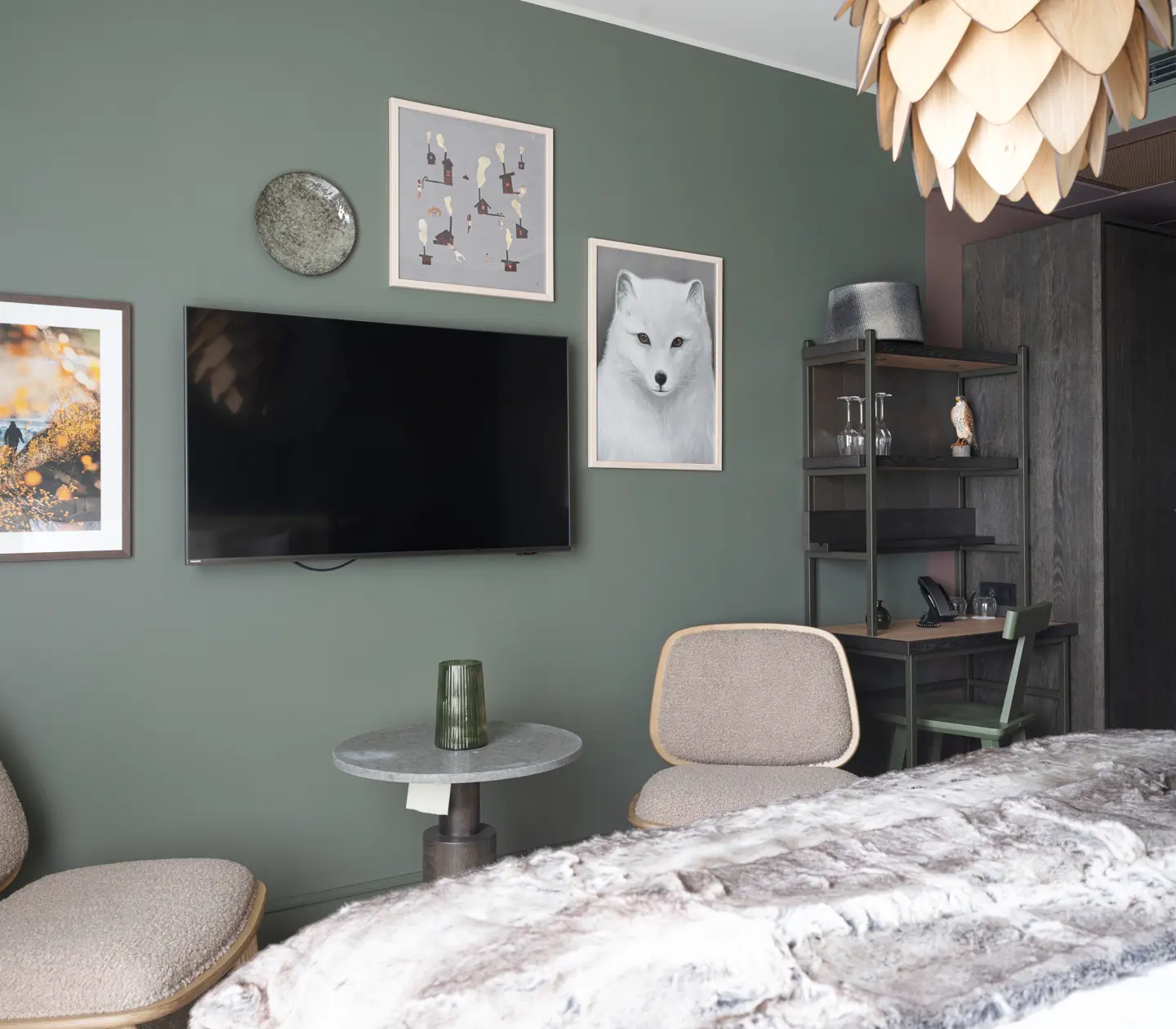 Modernt hotellrum med grön vägg, TV, konstverk och elegant inredning