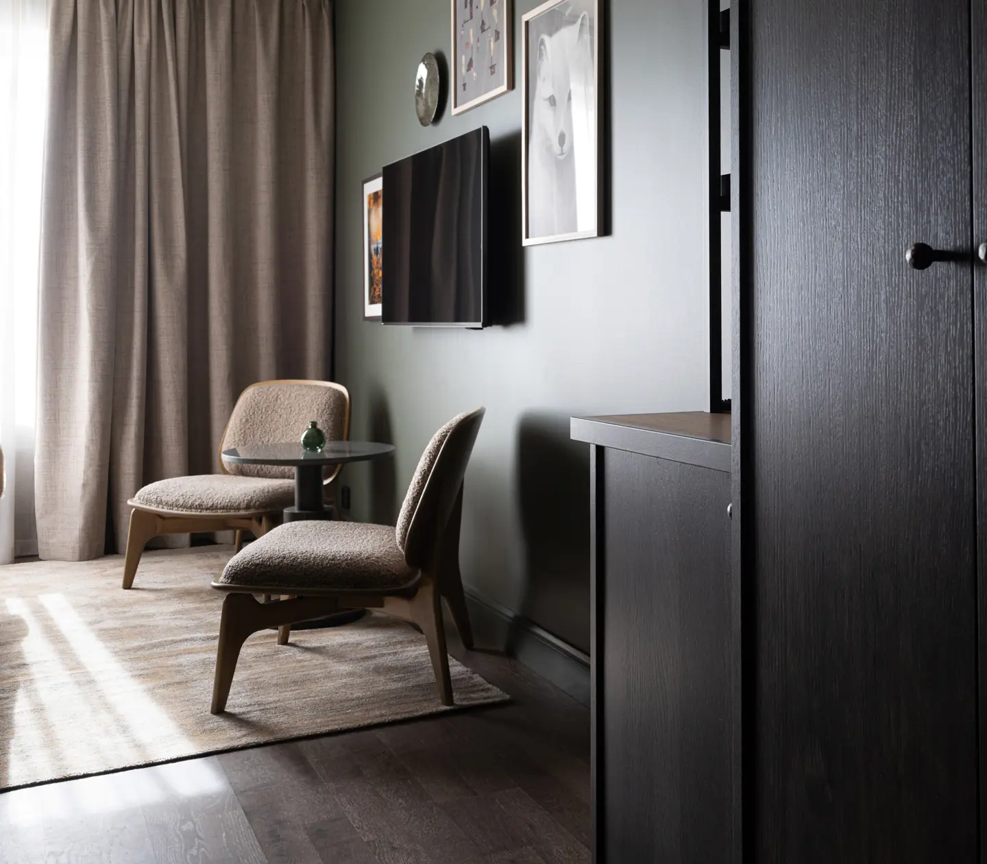 Cozy hotel room with bed, ceiling lamp, window, and armchairs.