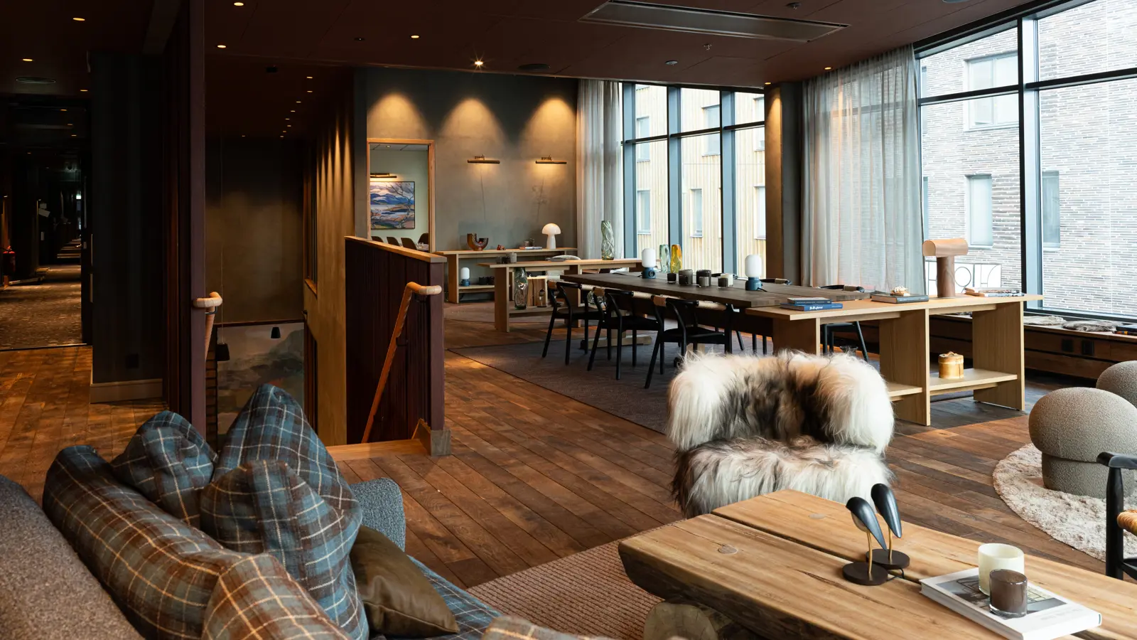 Mysig konferenslobby på kvällen med modern inredning, eleganta möbler och stämningsfull belysning, med utsikt över en naturnära omgivning genom stora fönster.