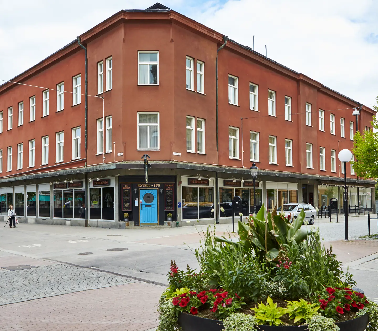 Facade of Hotel Bishops Arms with driveway and flower plantings in front