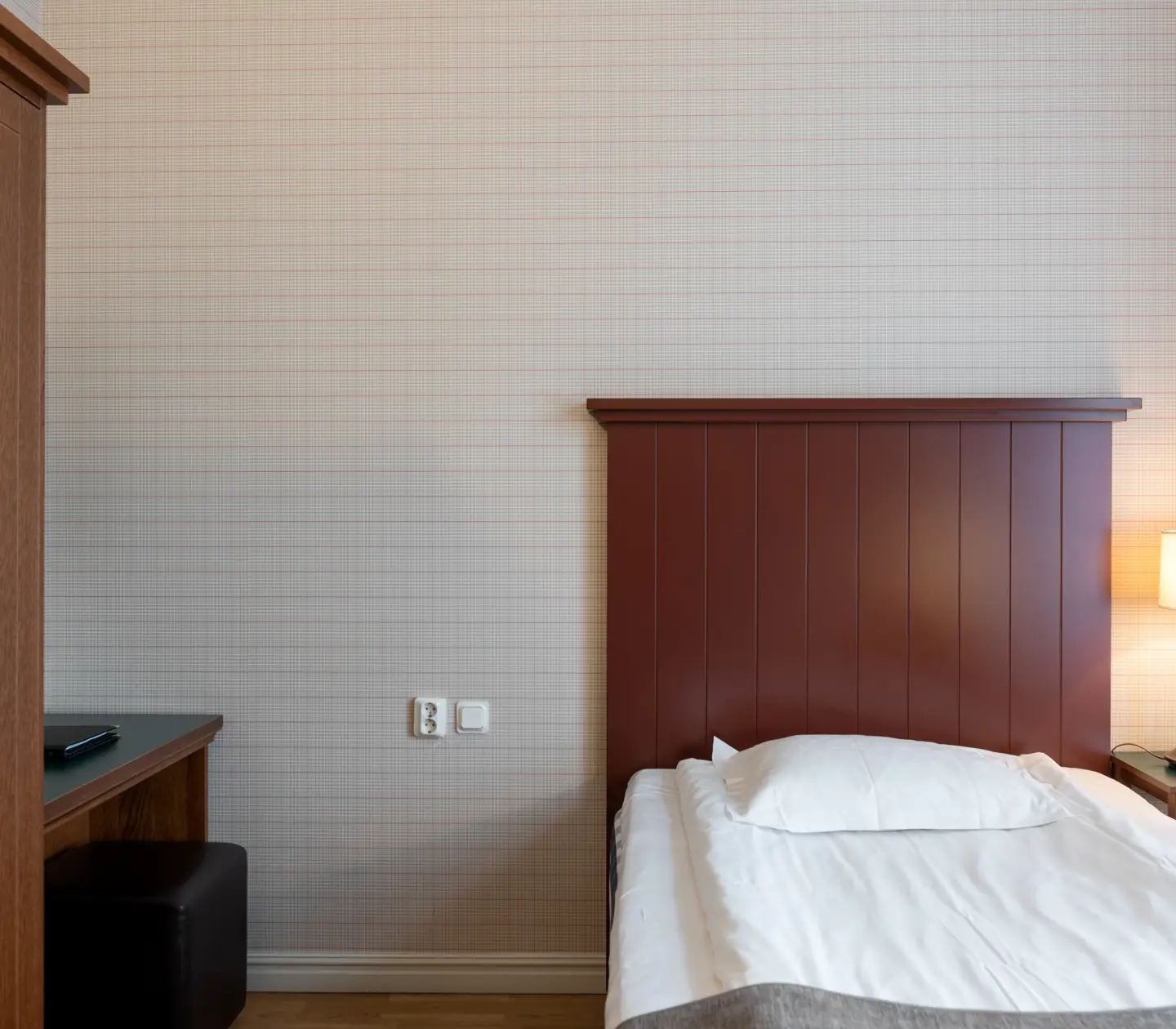 Hotel room with bed, wooden headboard and wardrobe