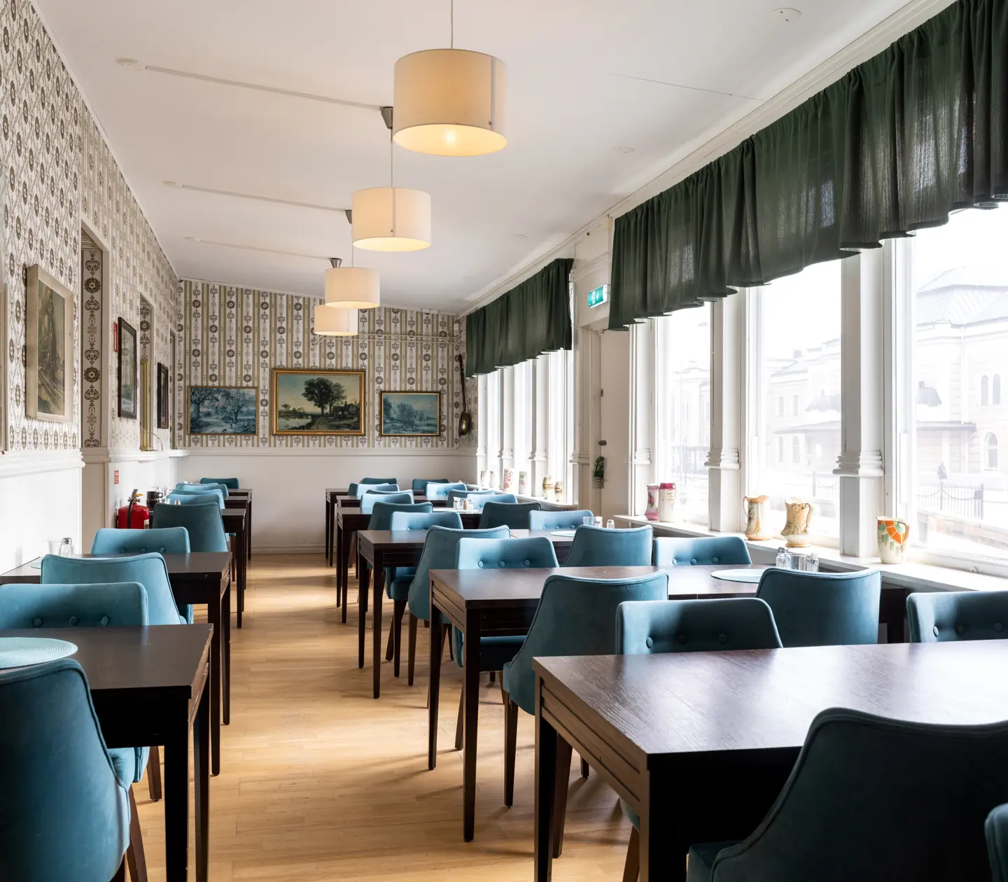 Breakfast dining room with many dining groups, many paintings and windows