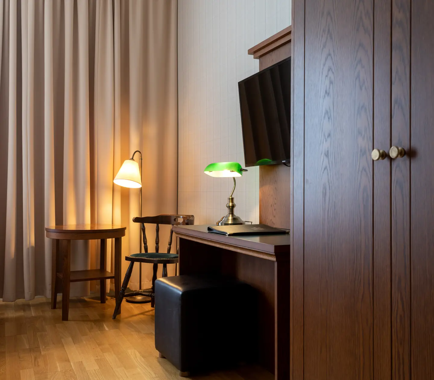 Cozy hotel room with curtain, desk and wardrobe