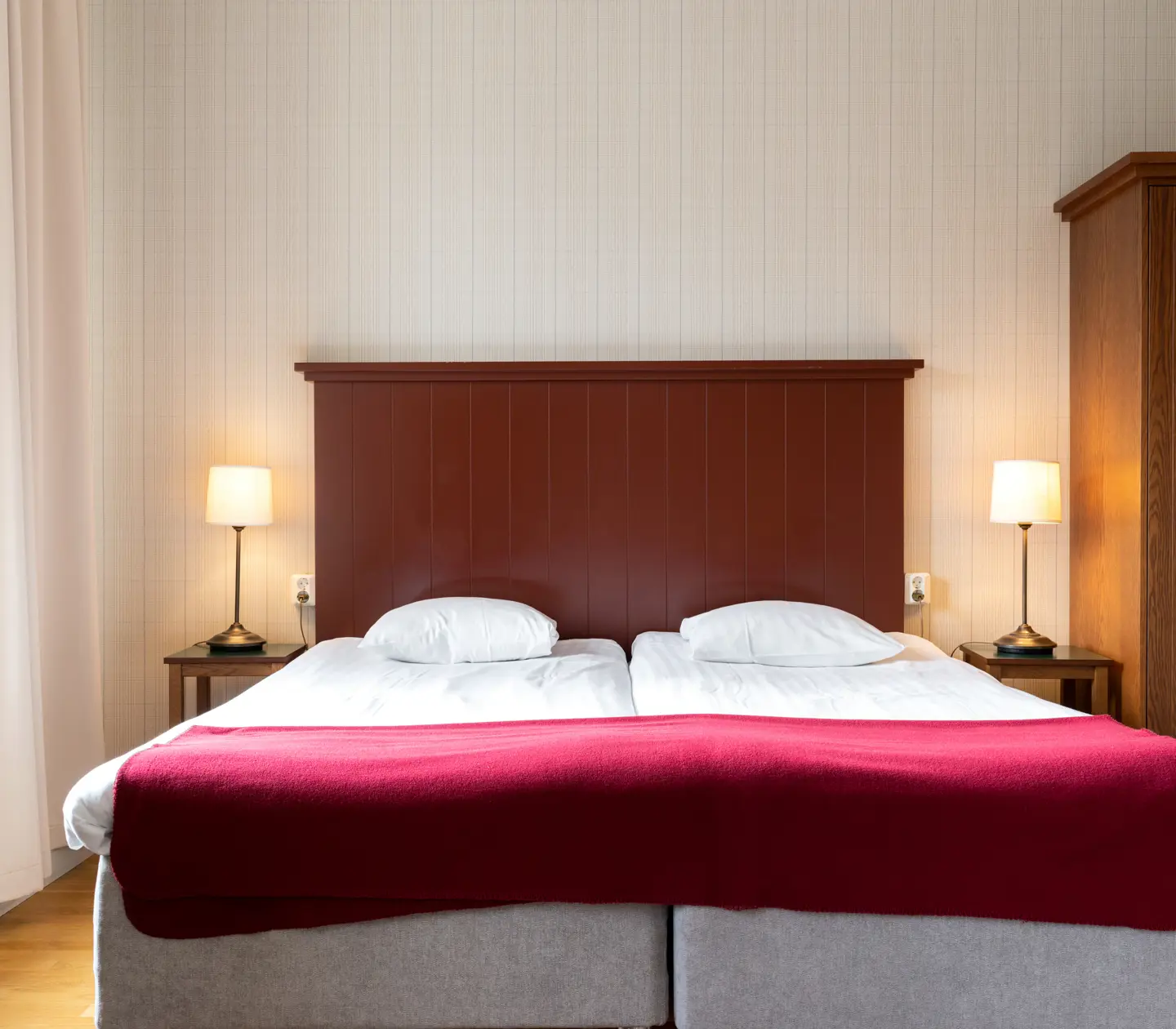 Cozy hotel room with bed, wooden headboard and bedside lamps
