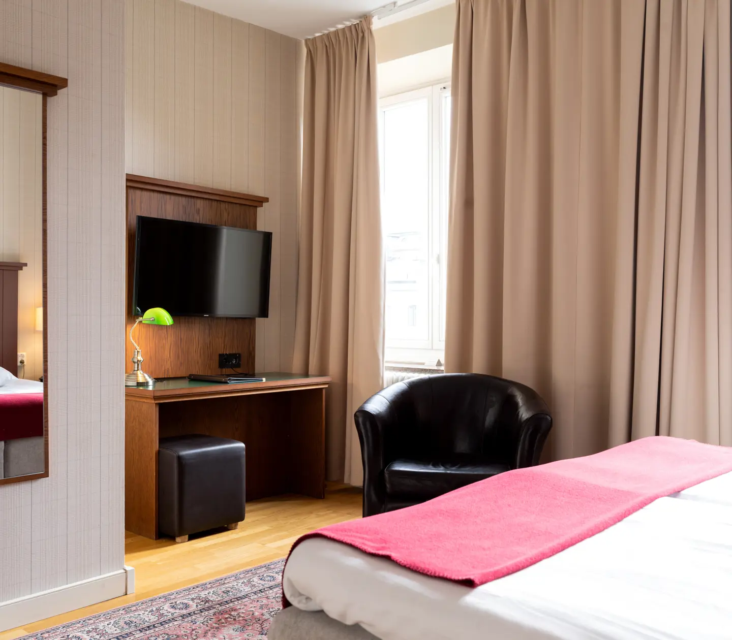 Cozy hotel room with desk, mirror and black leather armchair