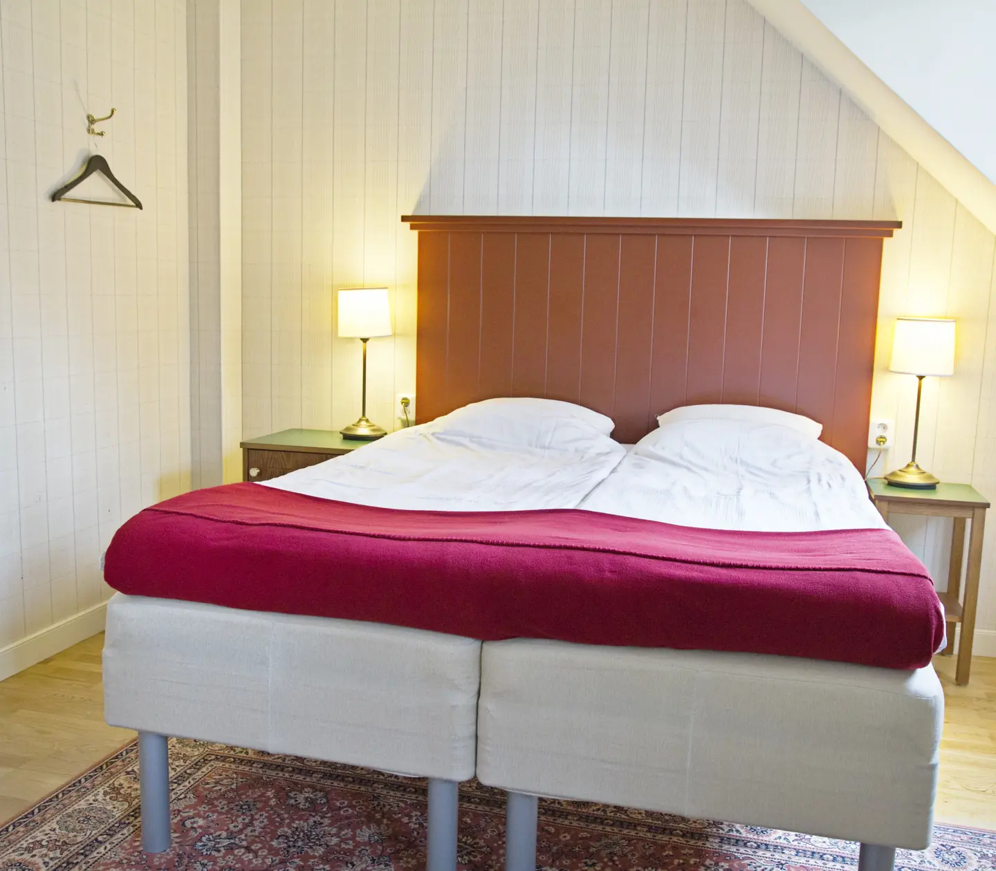 Cozy hotel room with bed, wooden headboard and bedside lamps