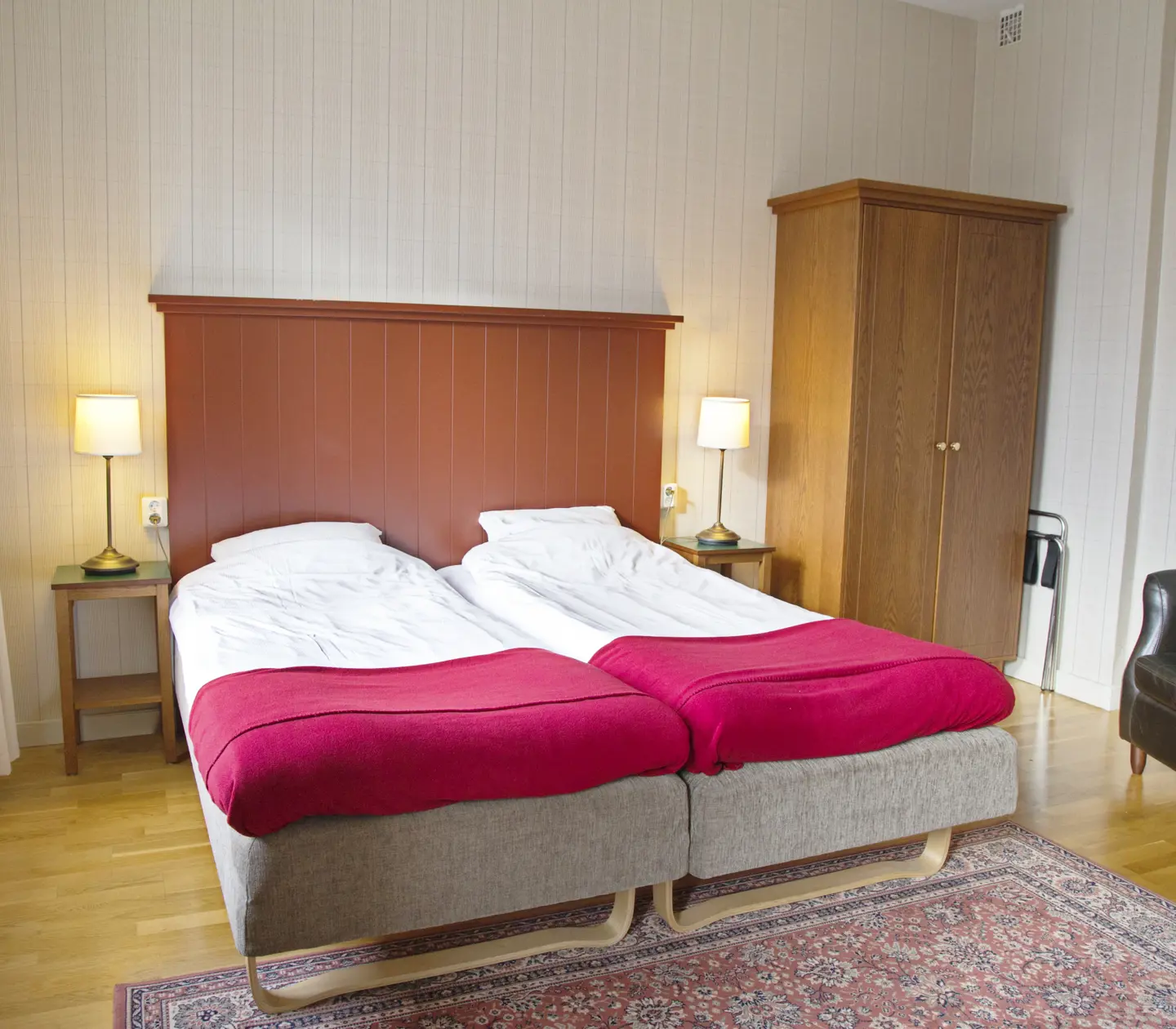 Cozy hotel room with bed, black leather armchair and wardrobe