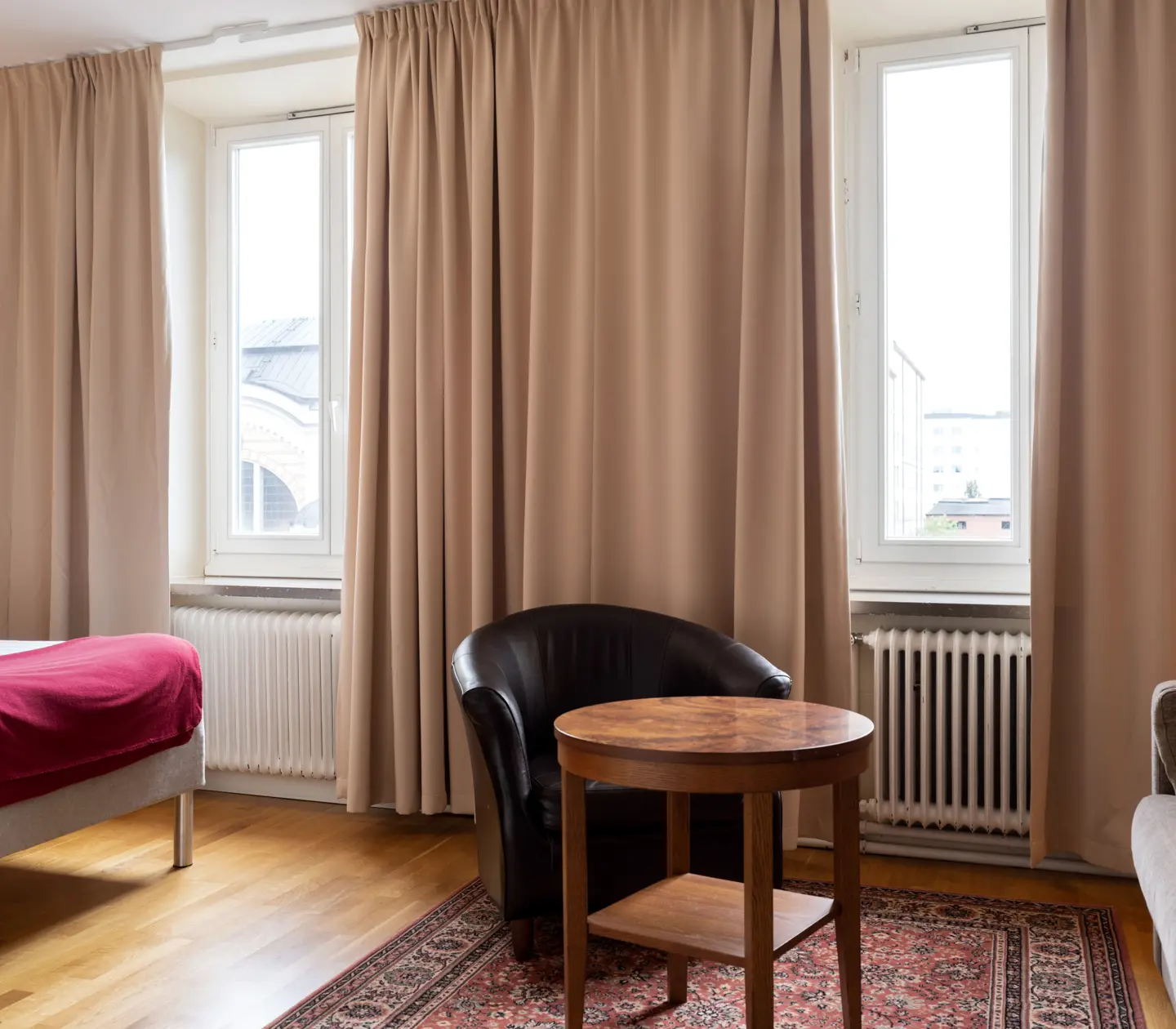 Cozy hotel room with bed, window and black leather armchair