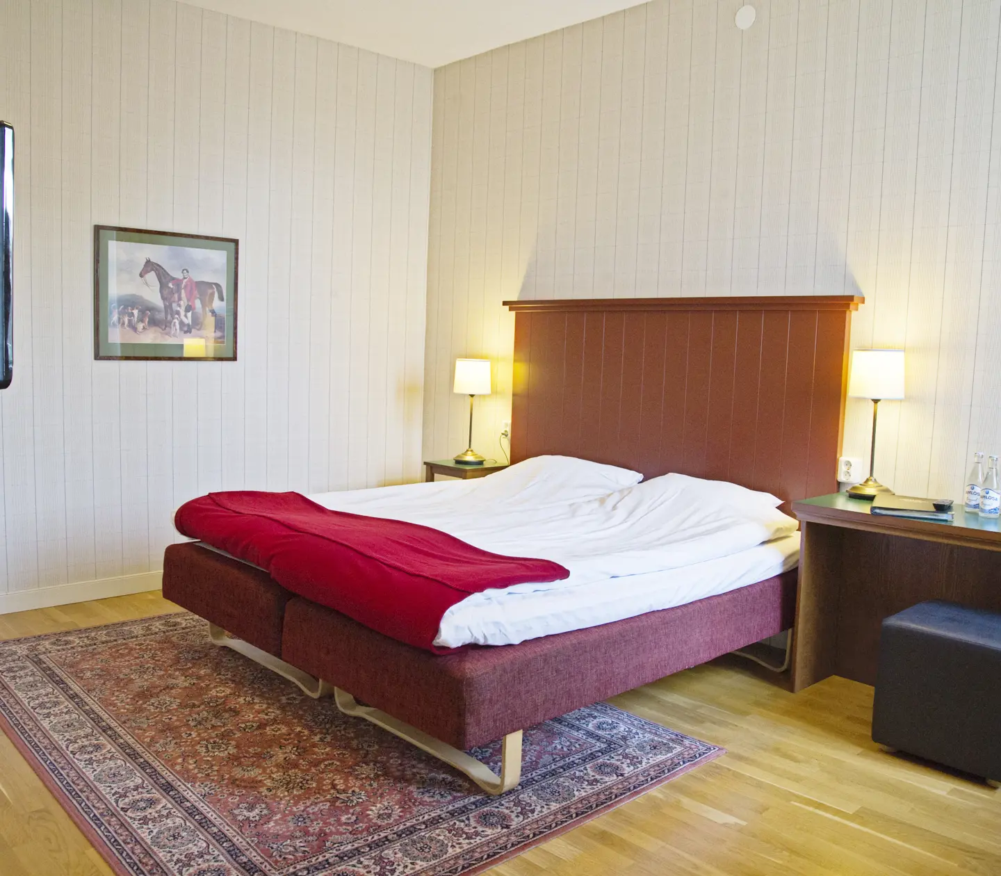Cozy hotel room with bed, wooden headboard and desk