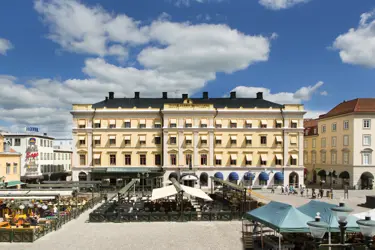 Stor gul byggnad i ett centrum med uteservering