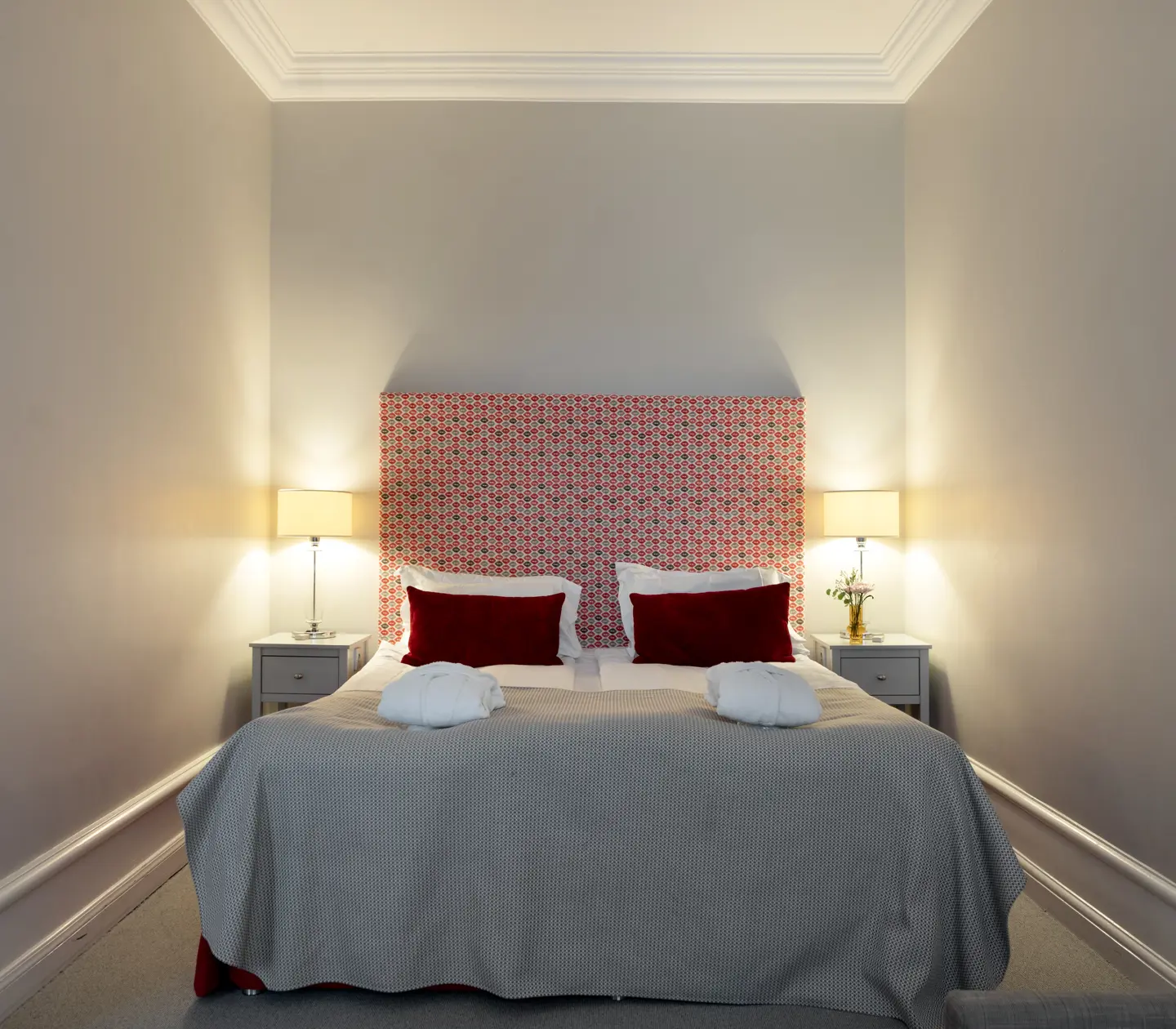 Hotel room with double bed, red headboard and bedside lamps