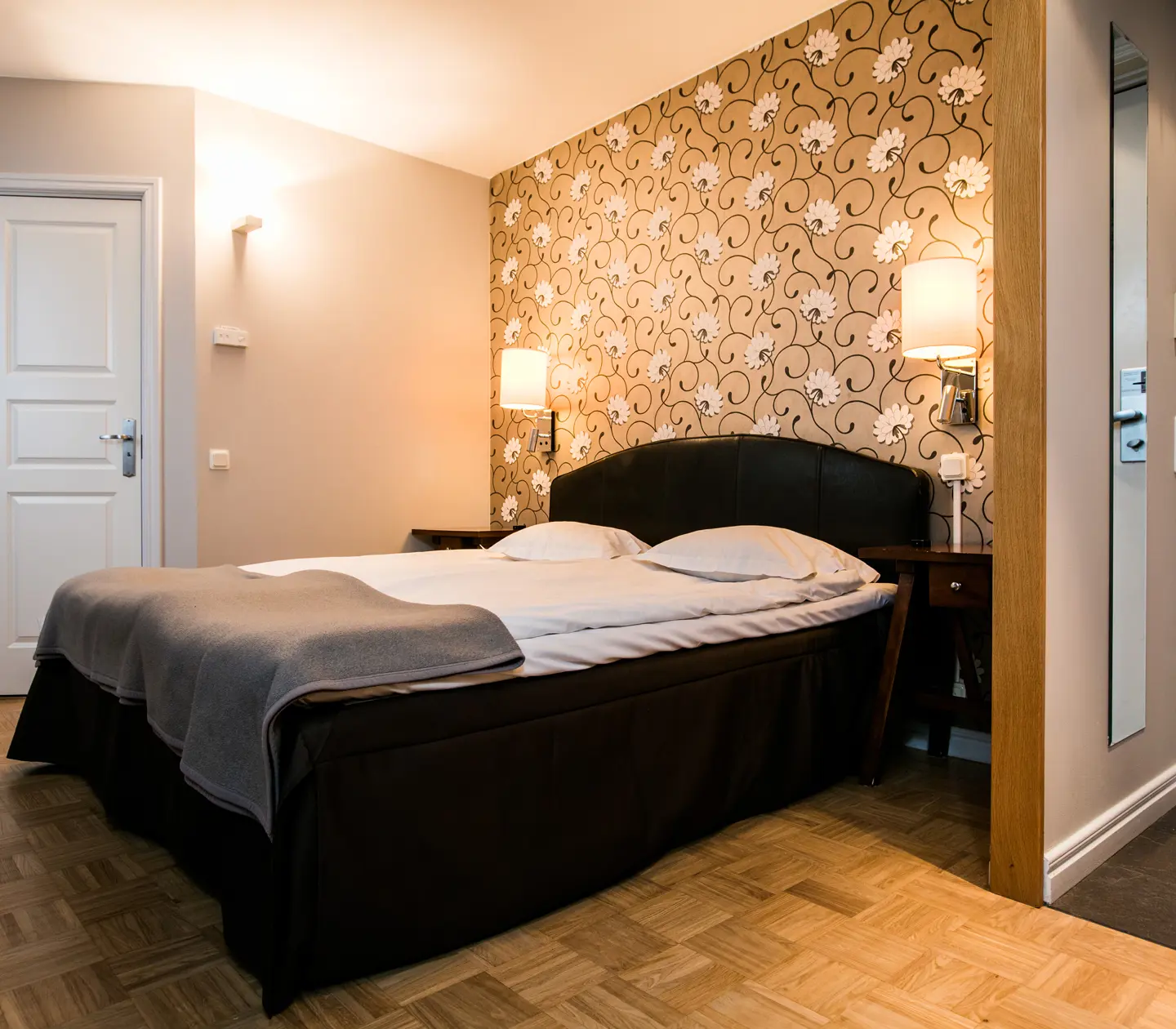 Hotel room with double bed, bedside lamps and mirror
