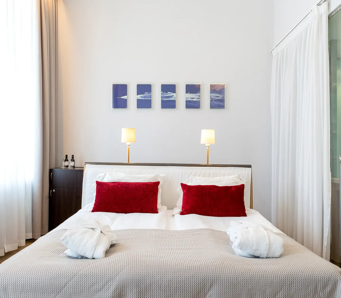 Bright hotel room with bed, bathrobes and TV
