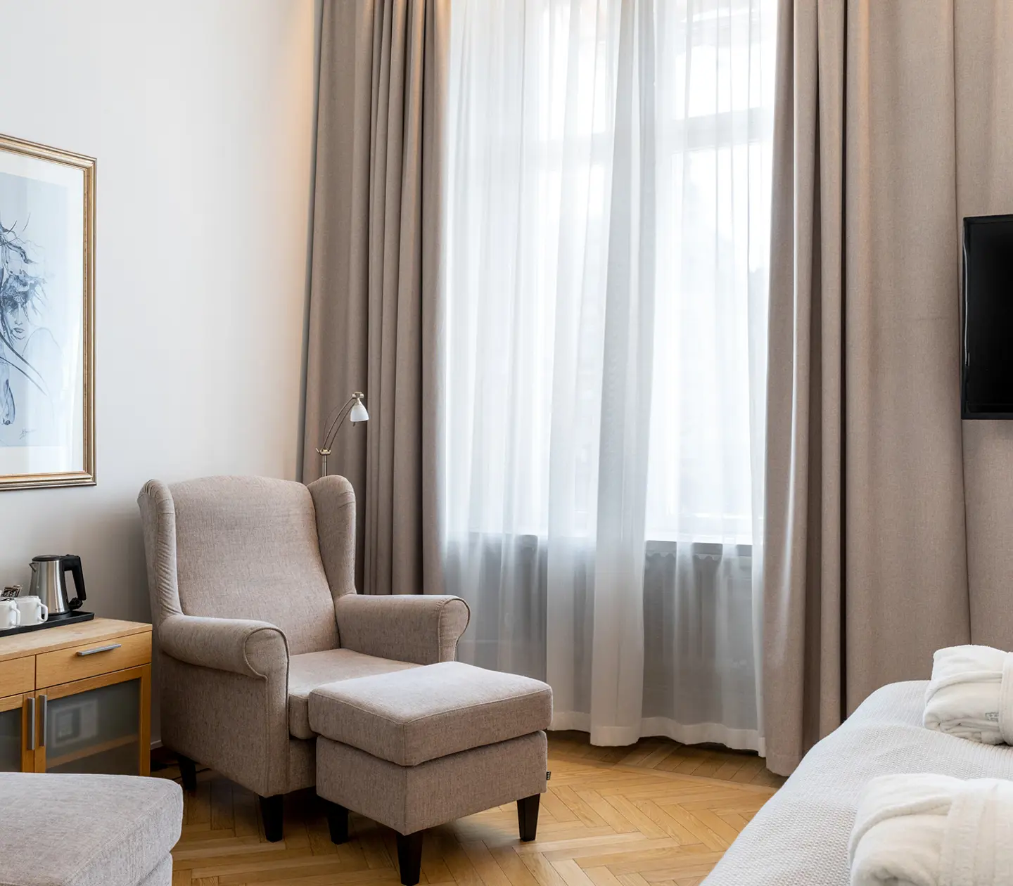 Bright hotel room with bathrobes, armchairs and TV