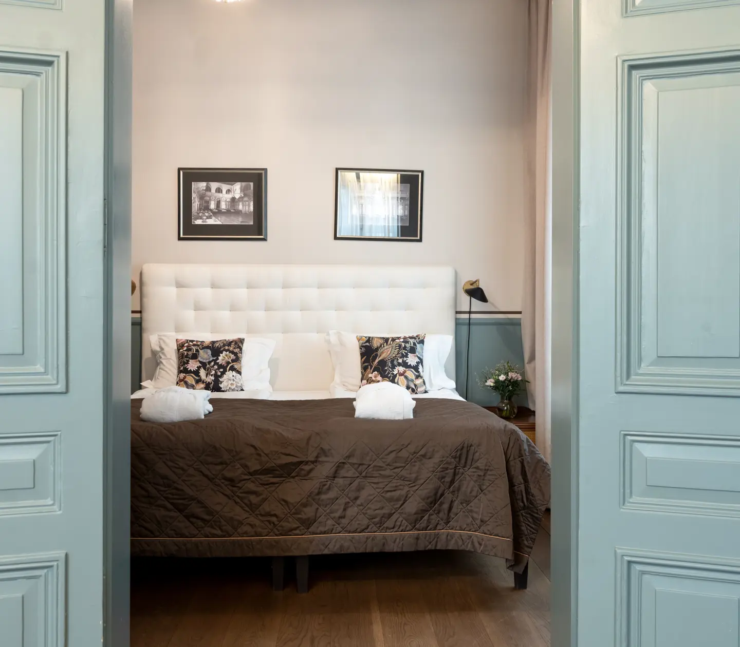 Bright suite with double bed, green open doors and paintings