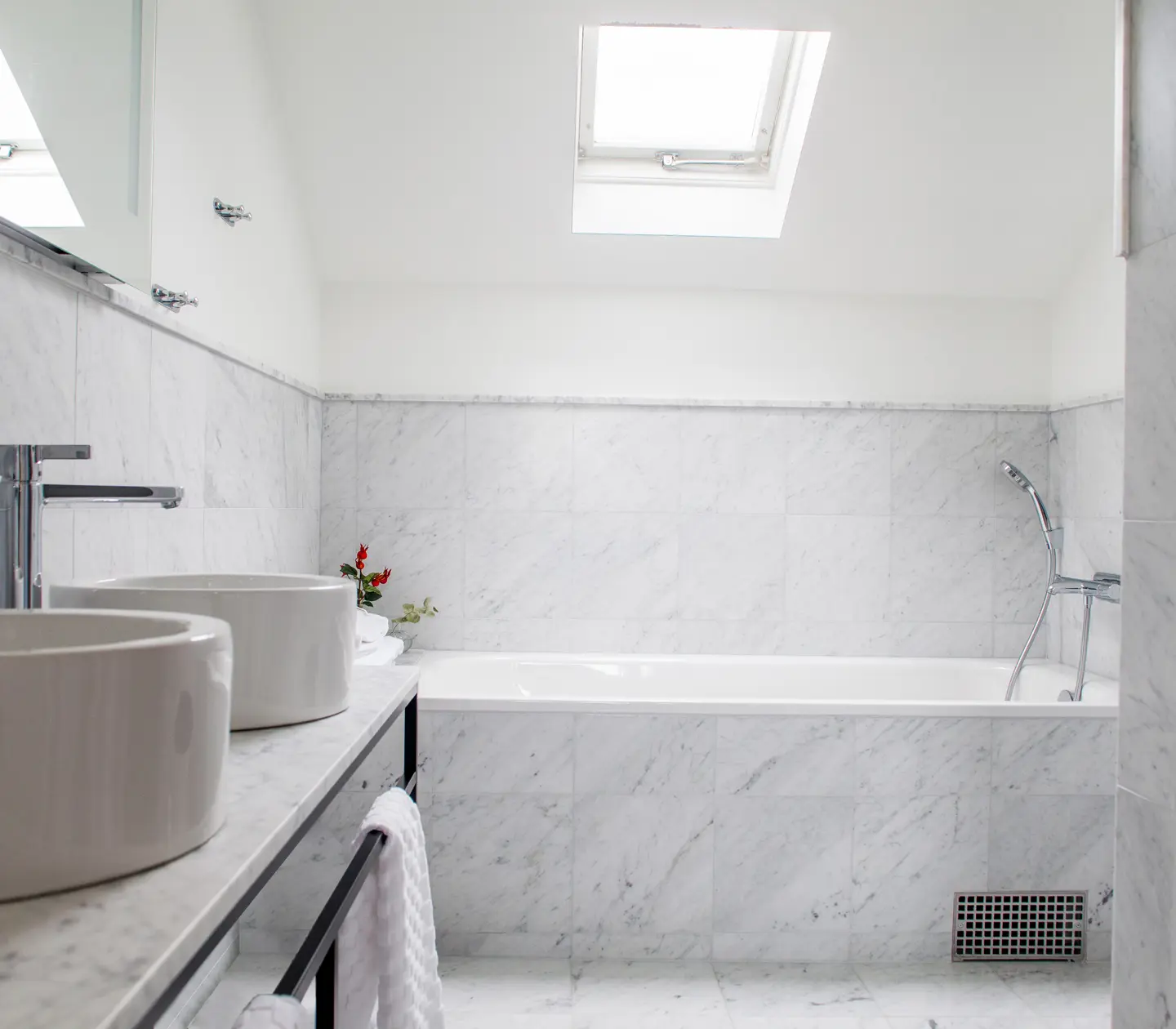Bright bathroom with bathtub, double sinks and skylight