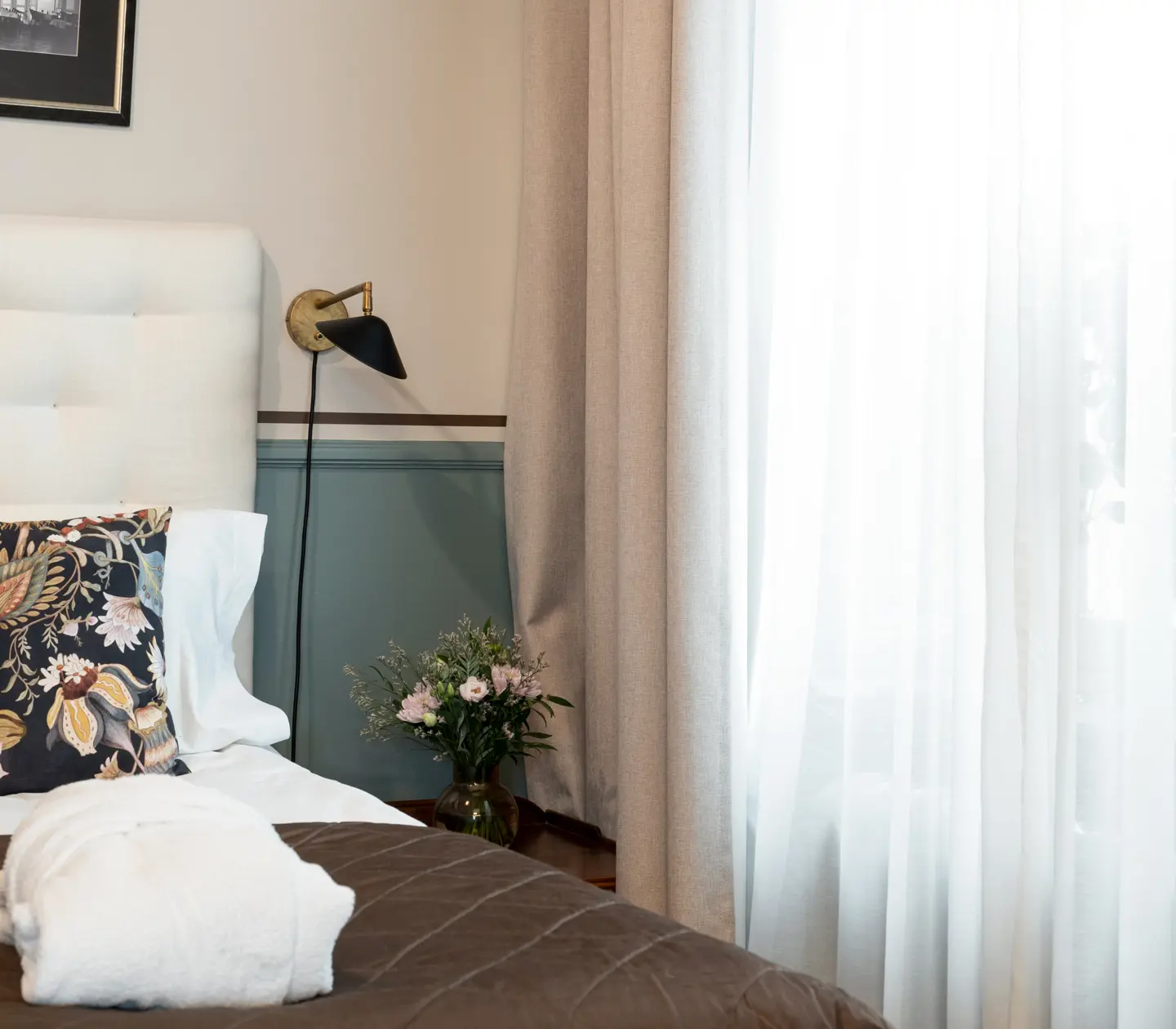 Bright suite with double bed, bedside lamp and bouquet